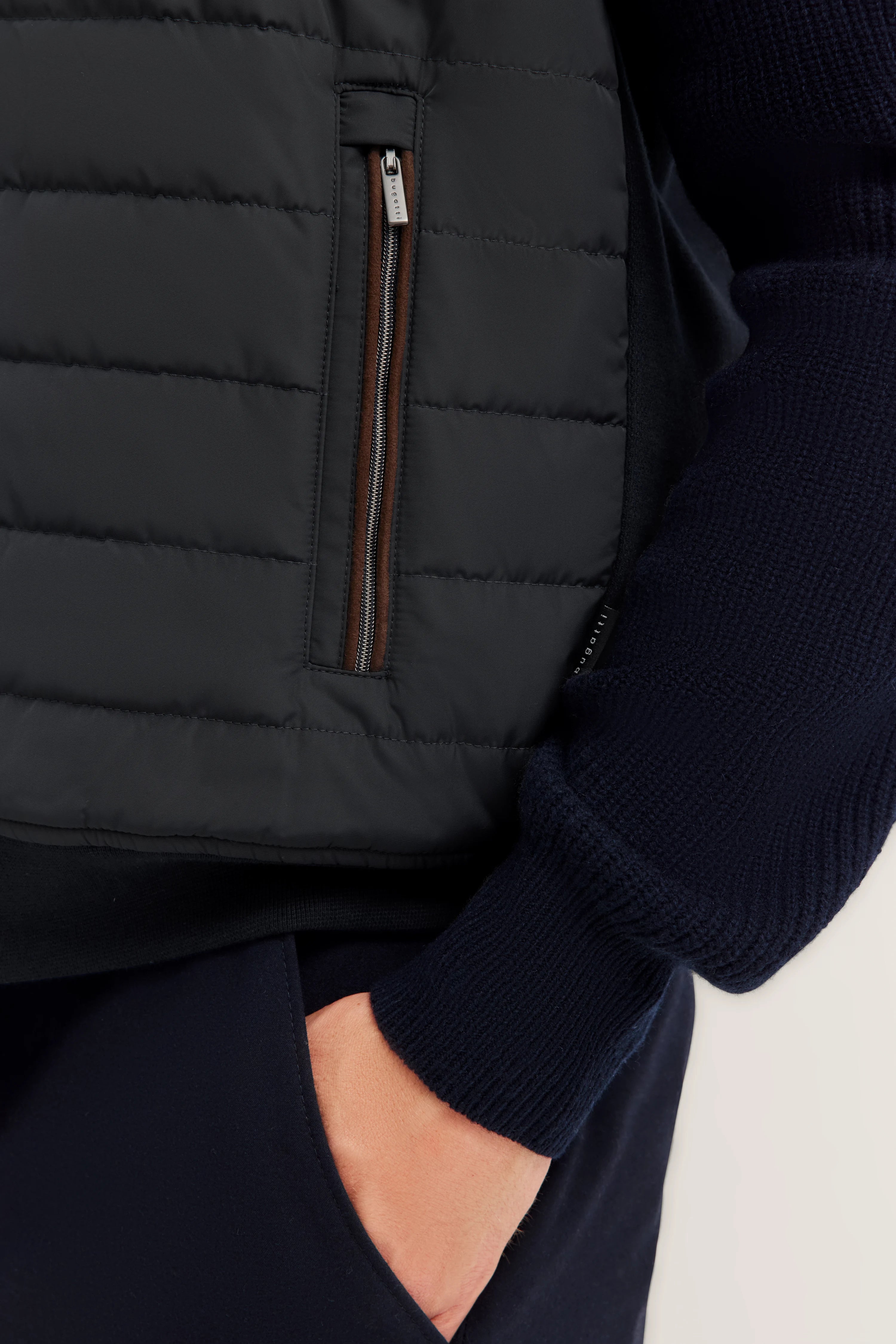 Dunkelblaue bugatti Steppjacke und Strickpullover, legeres Detailbild mit Taschenansicht.