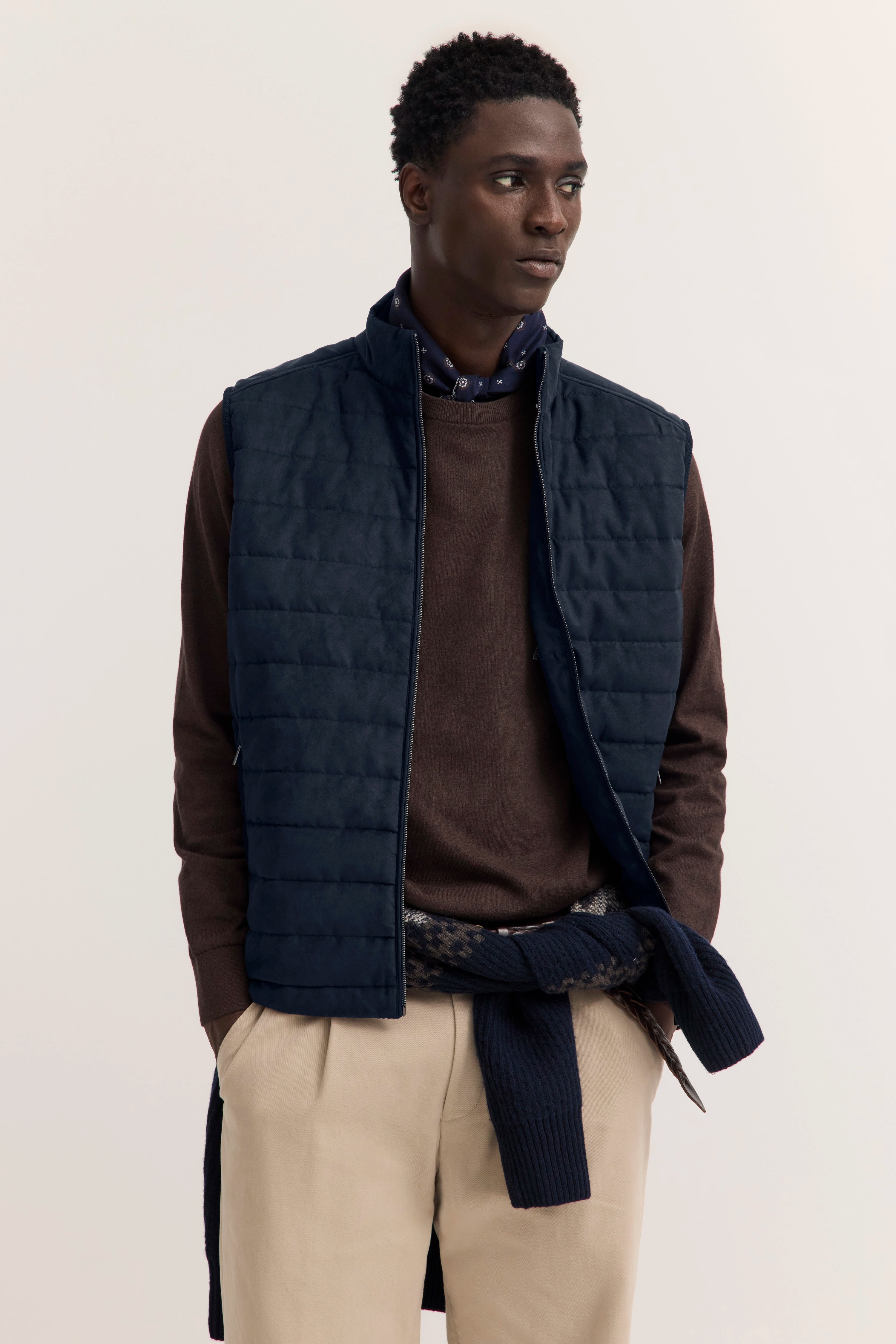 Model trägt bugatti Weste in Navy, braunen Pullover, beige Hose