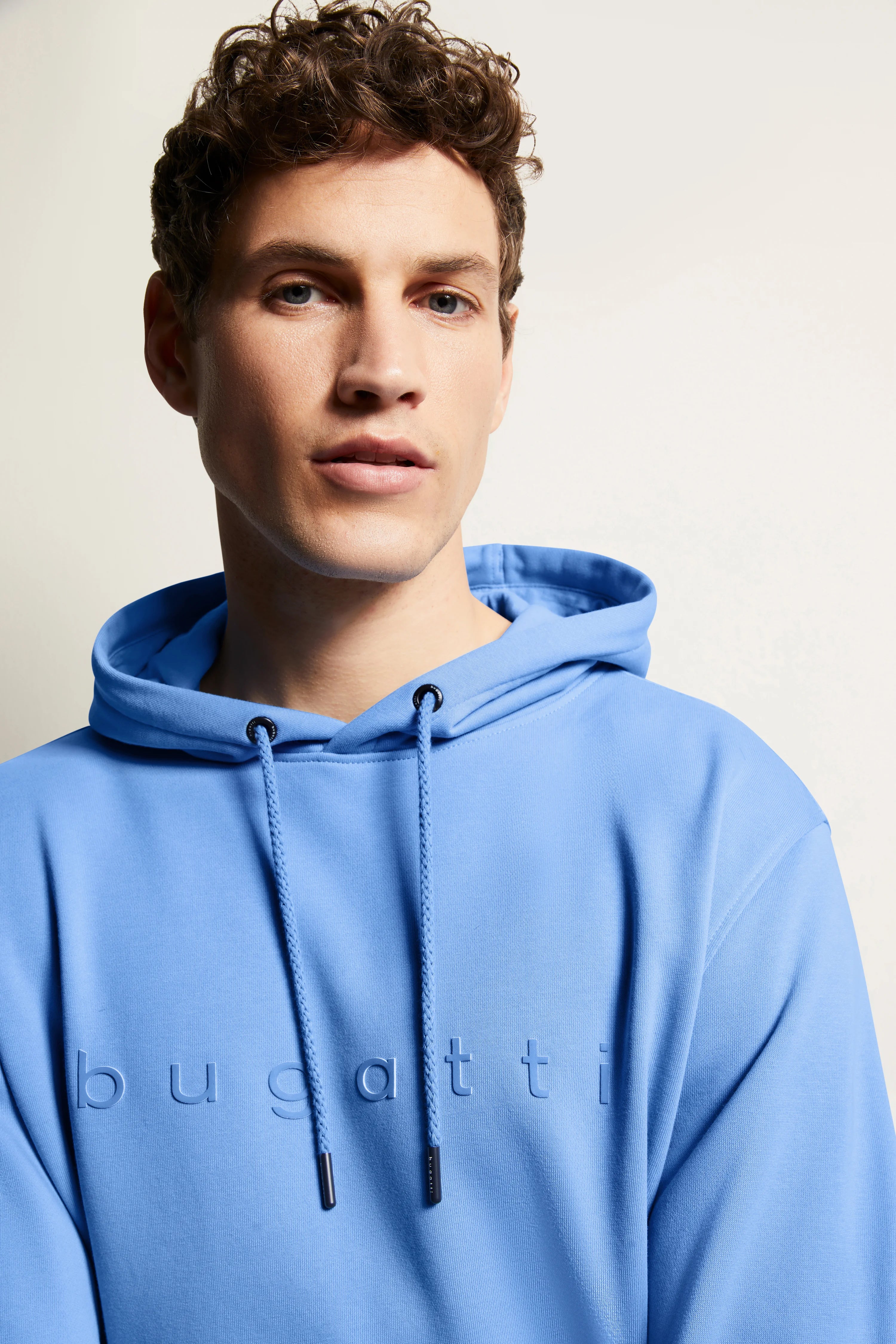 Blauer bugatti Hoodie auf Model, legeres Posing, stilvoll und entspannt.