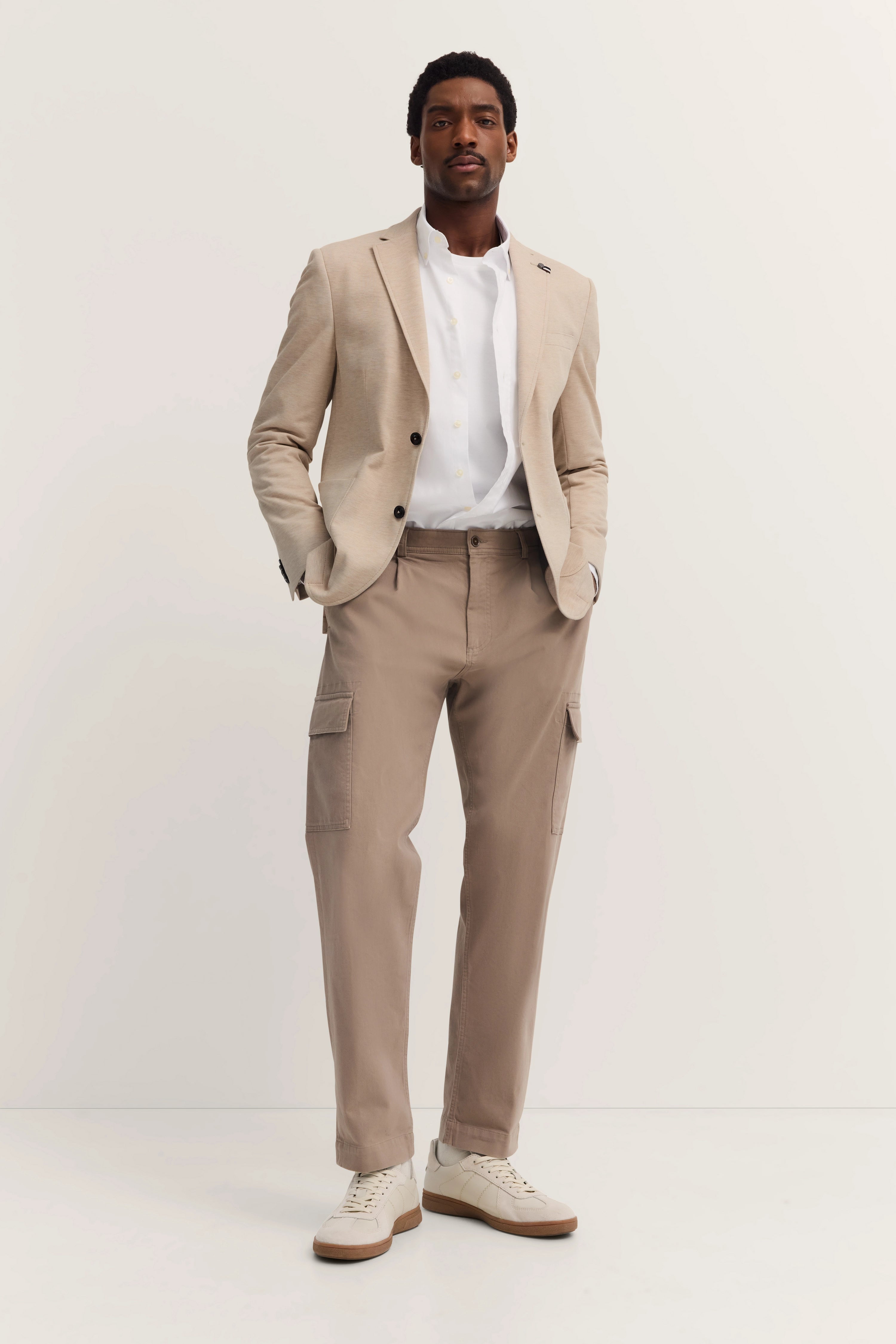 Beiger bugatti Blazer, weißes Hemd, beige Cargo-Hose, Model stehend, lässige Pose.