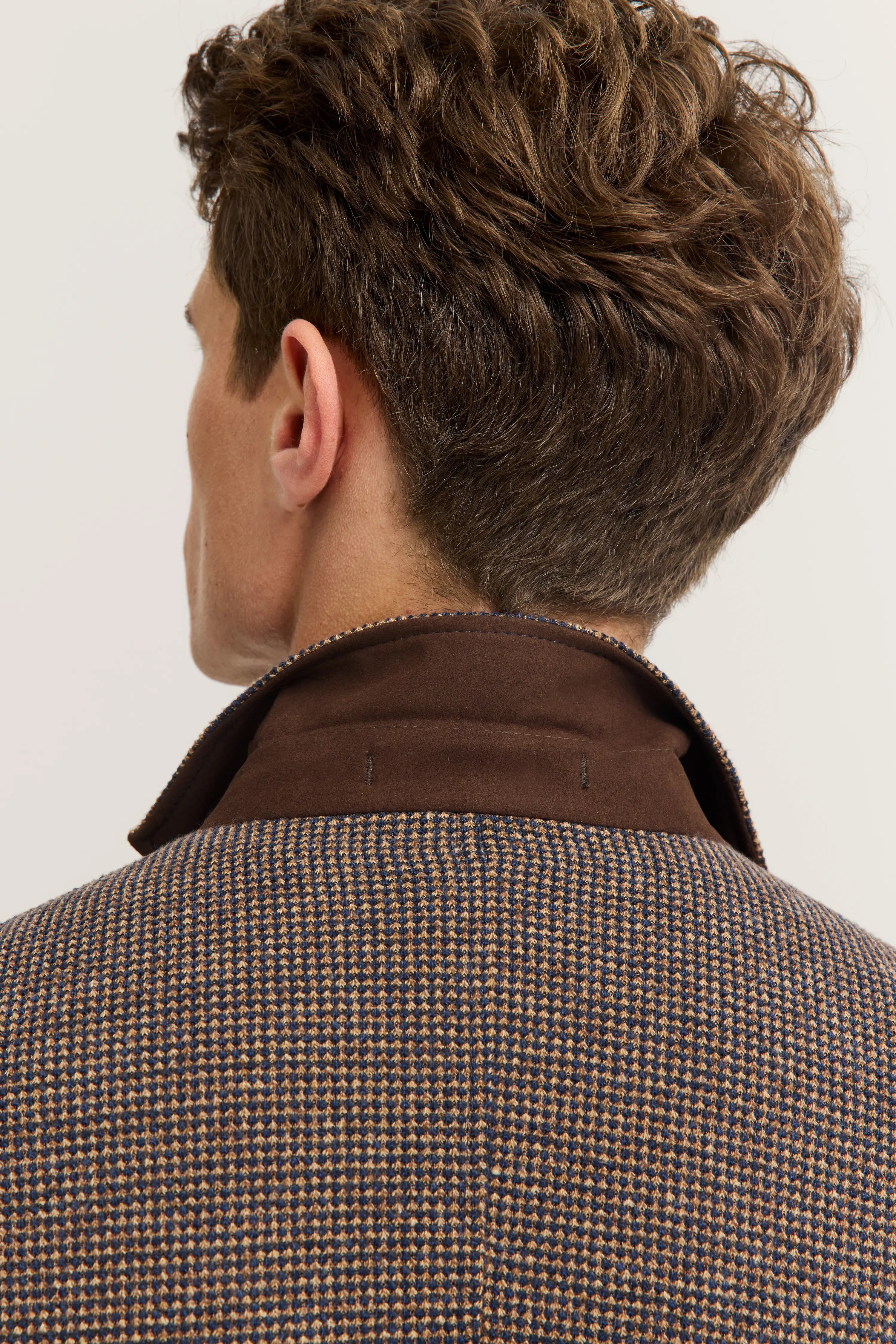 Back view of man in brown checkered bugatti coat, focused on collar.