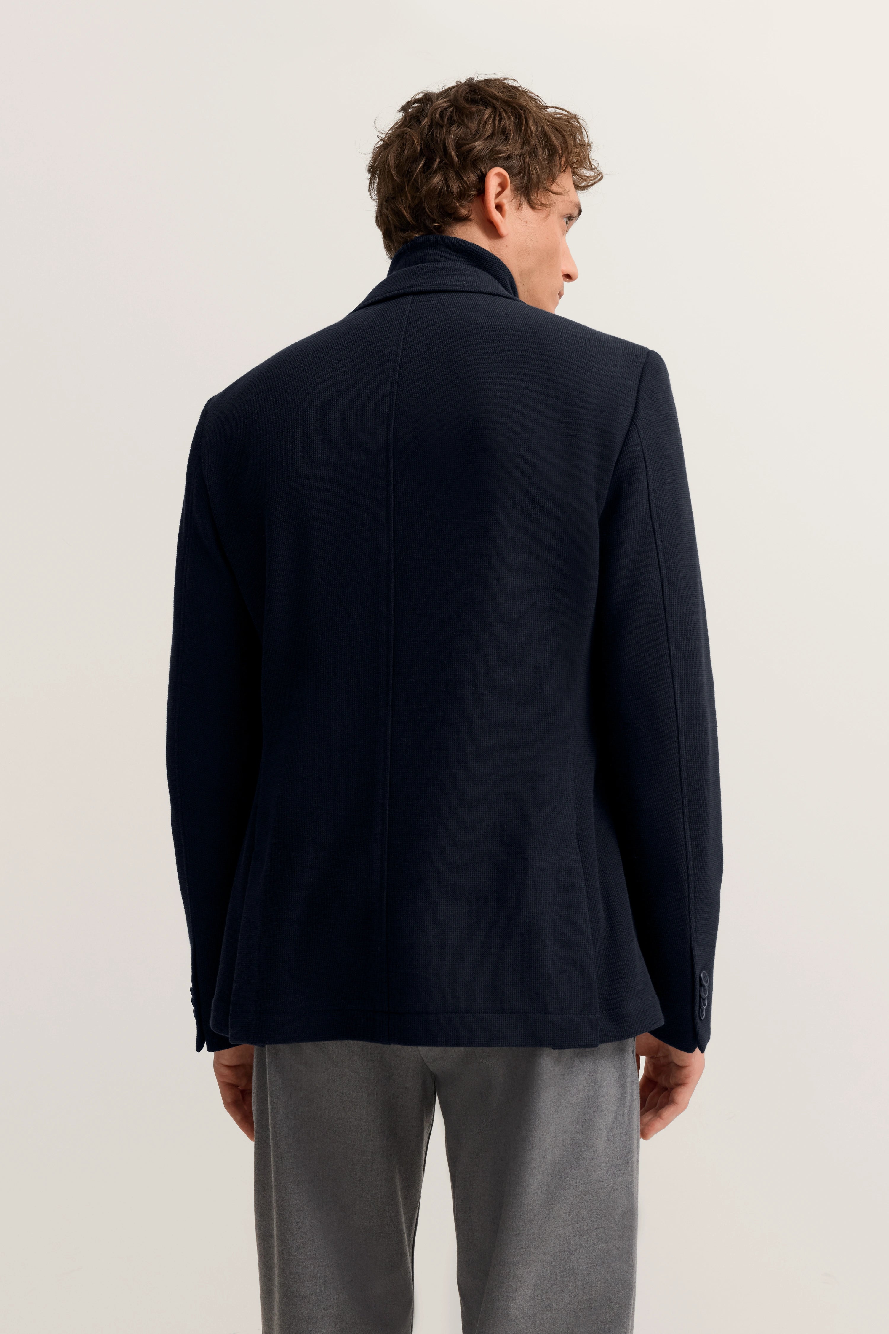 Navy Blazer von bugatti, Rückansicht auf Modell, kombiniert mit grauer Hose.