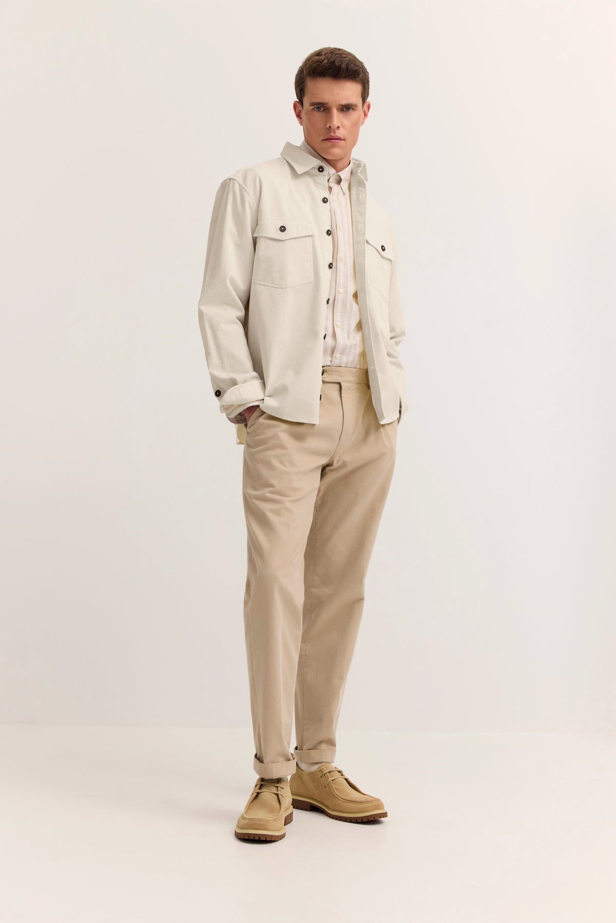 bugatti Model in beiger Jacke und Hose, lässige Pose, zeitlose Eleganz.