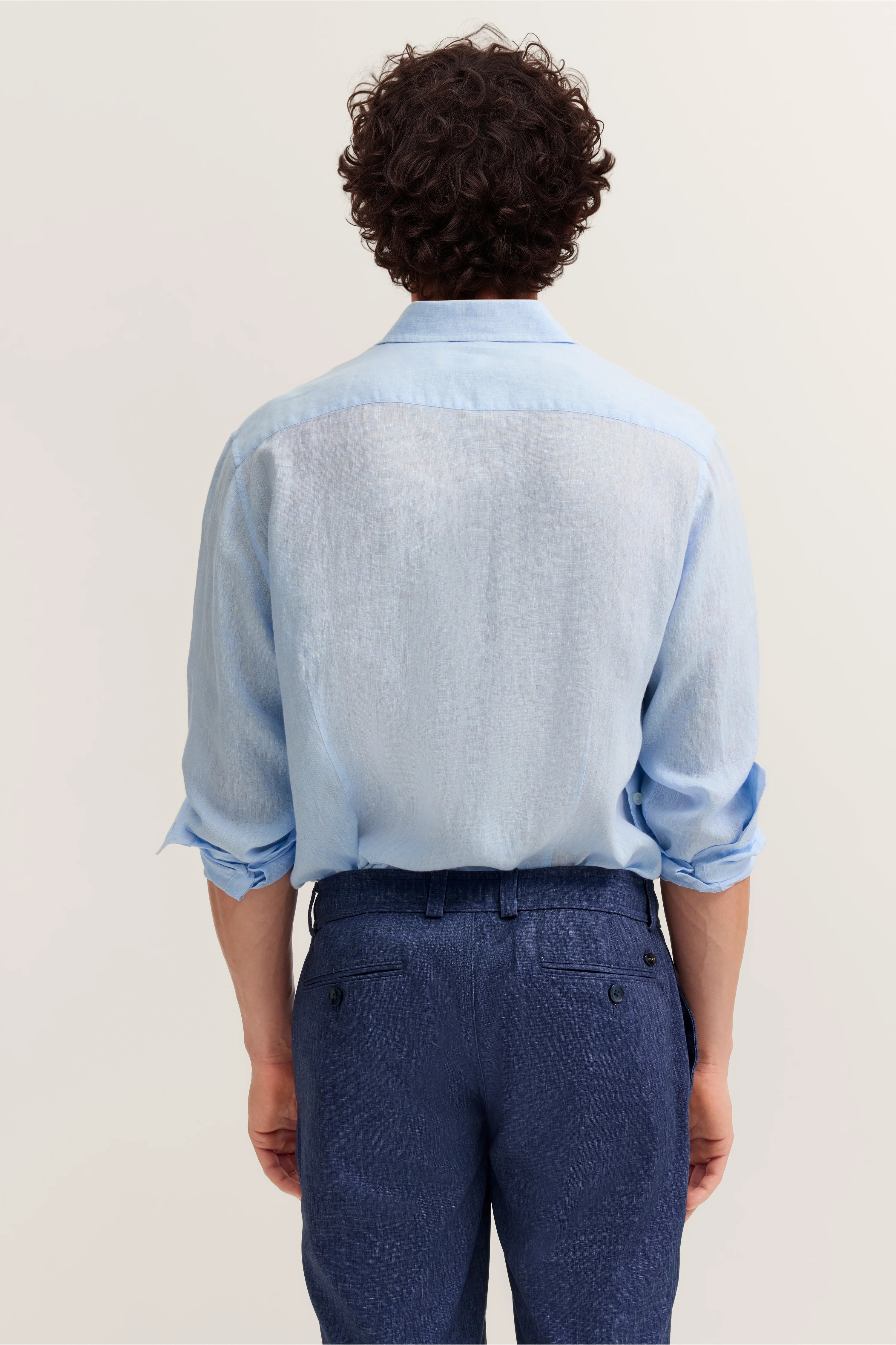 Hellblaues Hemd und dunkelblaue Hose, Rückansicht, legeres Modelbild, Ärmel hochgekrempelt.