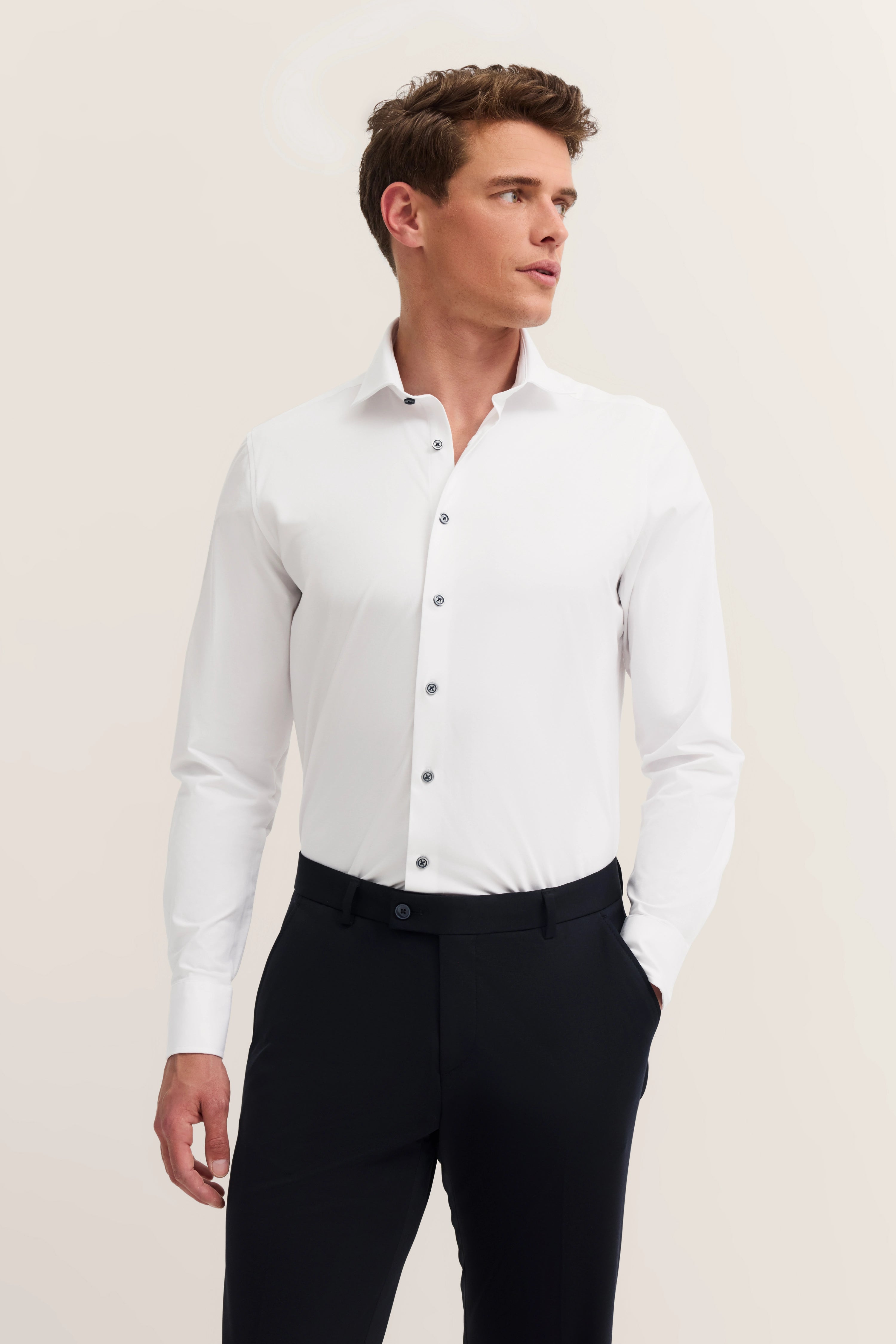 Wit bugatti overhemd en zwarte broek op model, nonchalante pose.