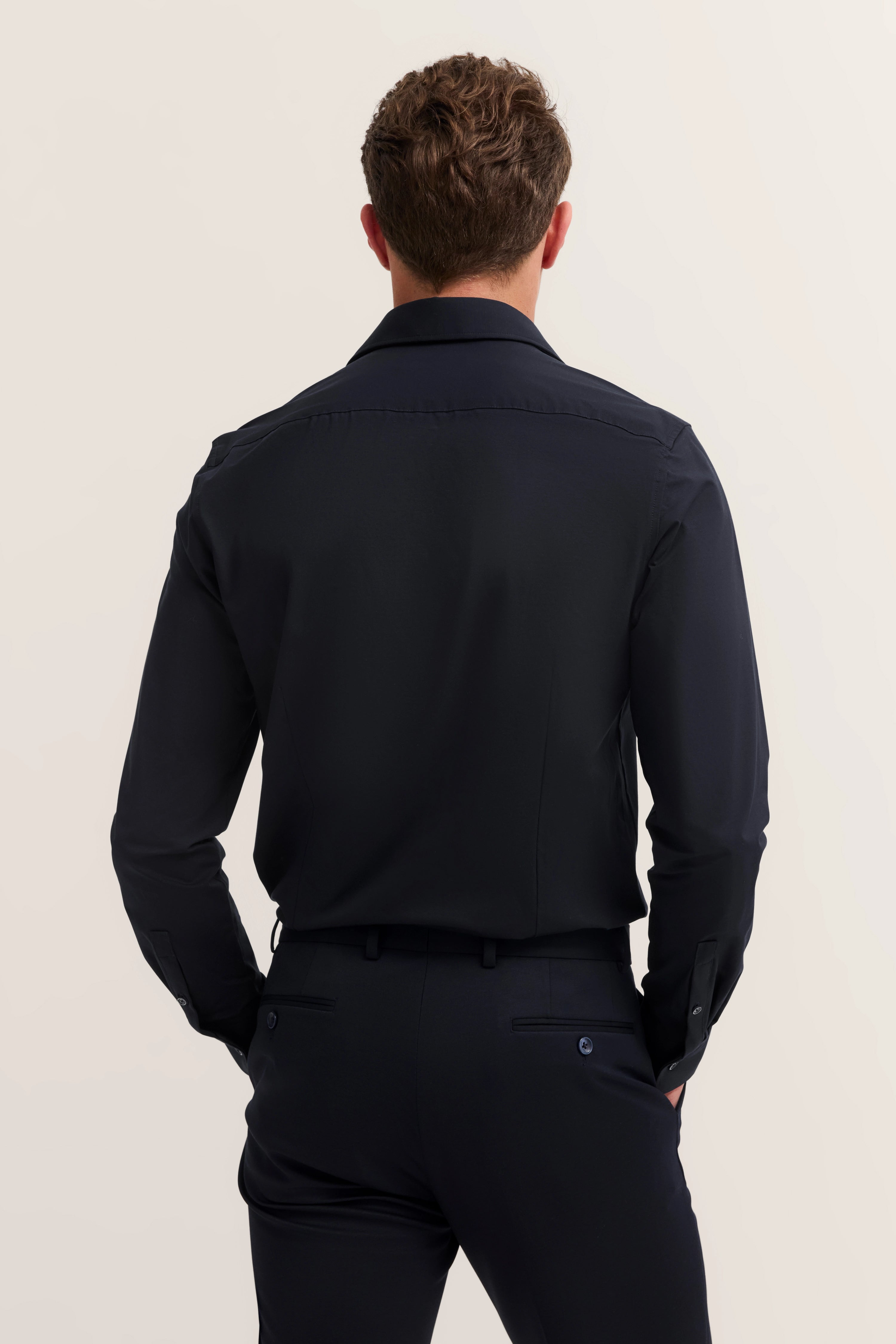 bugatti model in donkerblauw shirt en broek, rugaanzicht, casual houding.