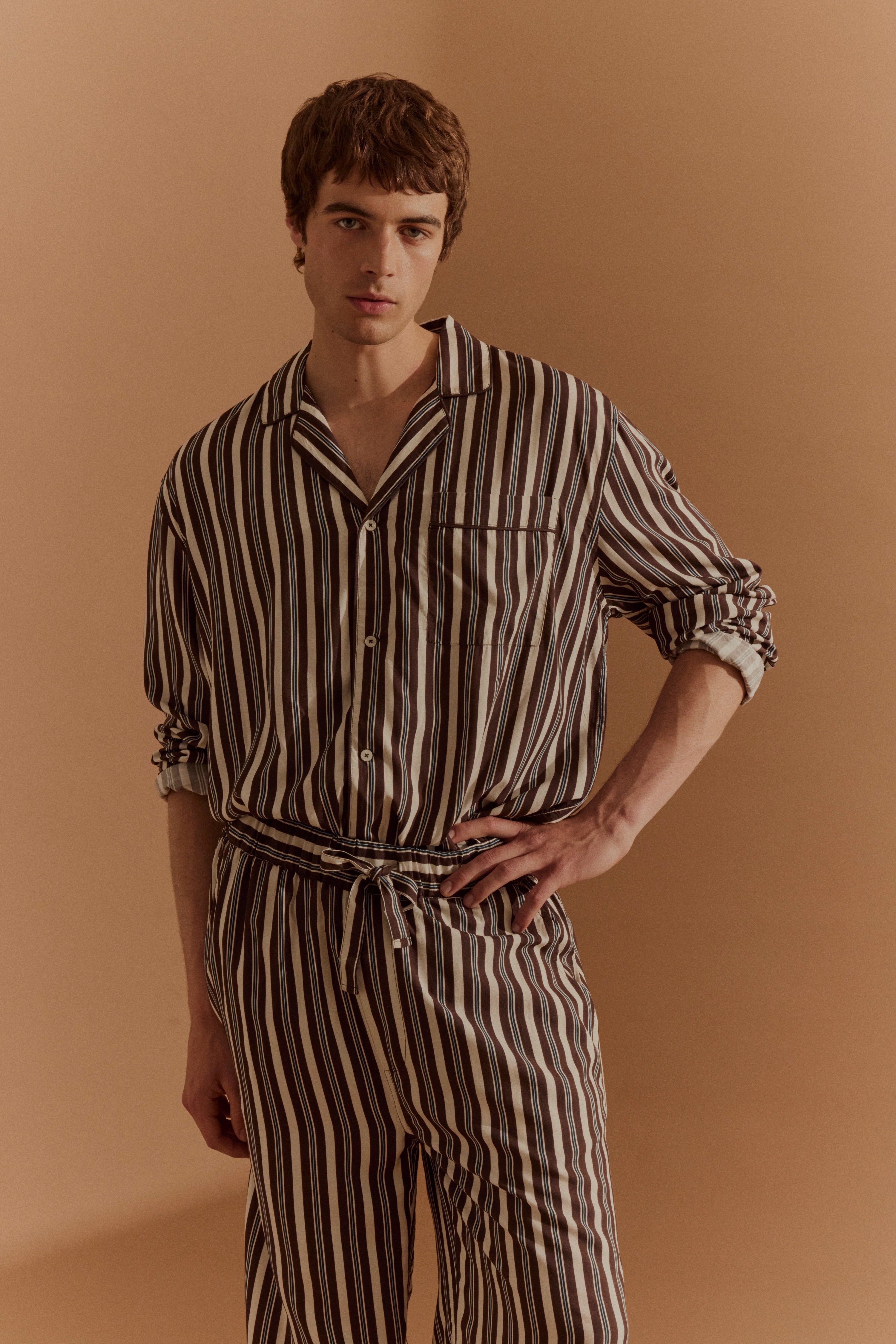Streifenpyjama in Braun und Weiß, Modelbild, entspannte Pose.