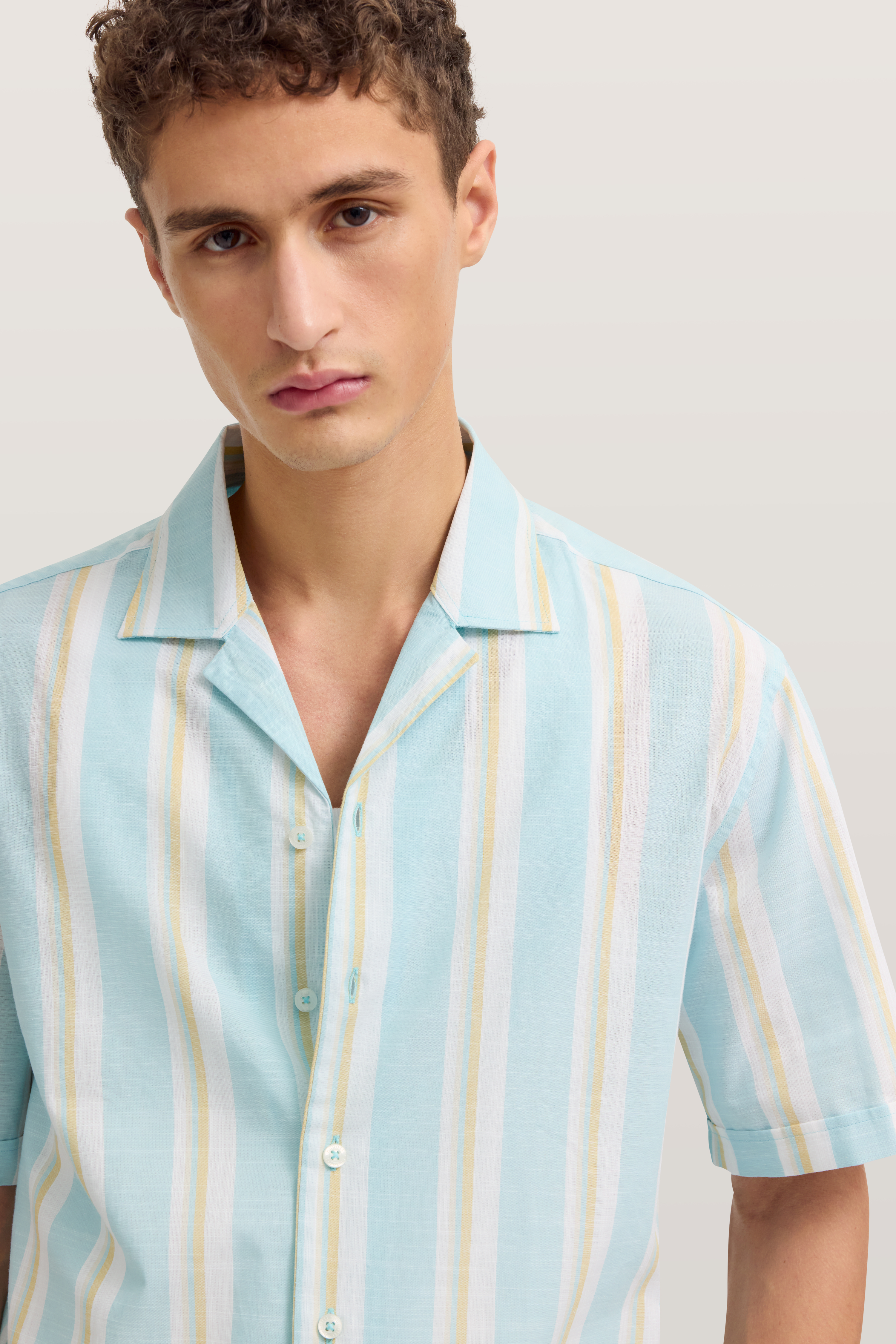 Herrenhemd mit Streifenmuster in Blau und Gelb, Modelbild, lockere Haltung.