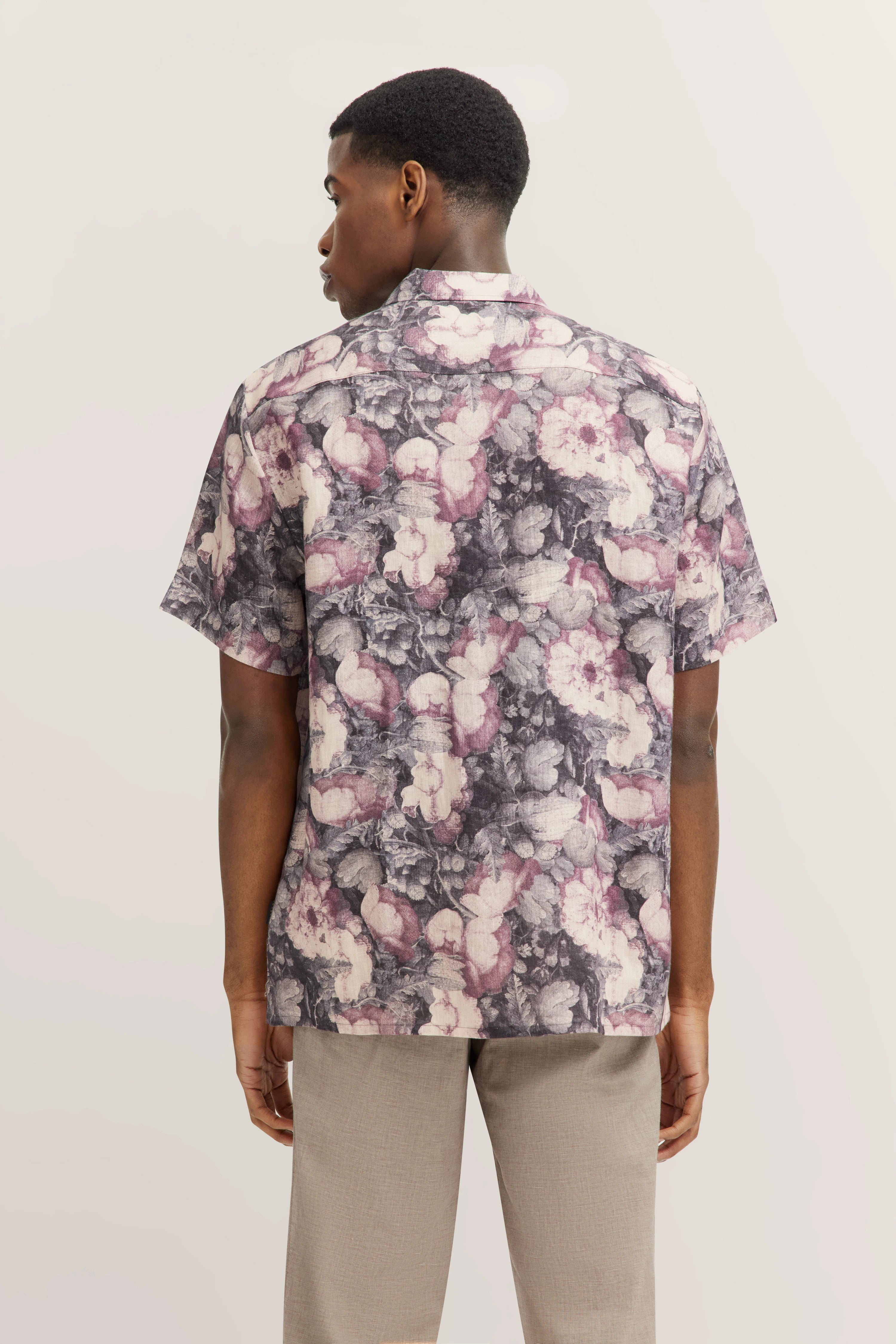 Bloemenmotief overhemd in paars en beige, model van achteren, gecombineerd met lichtgrijze broek.