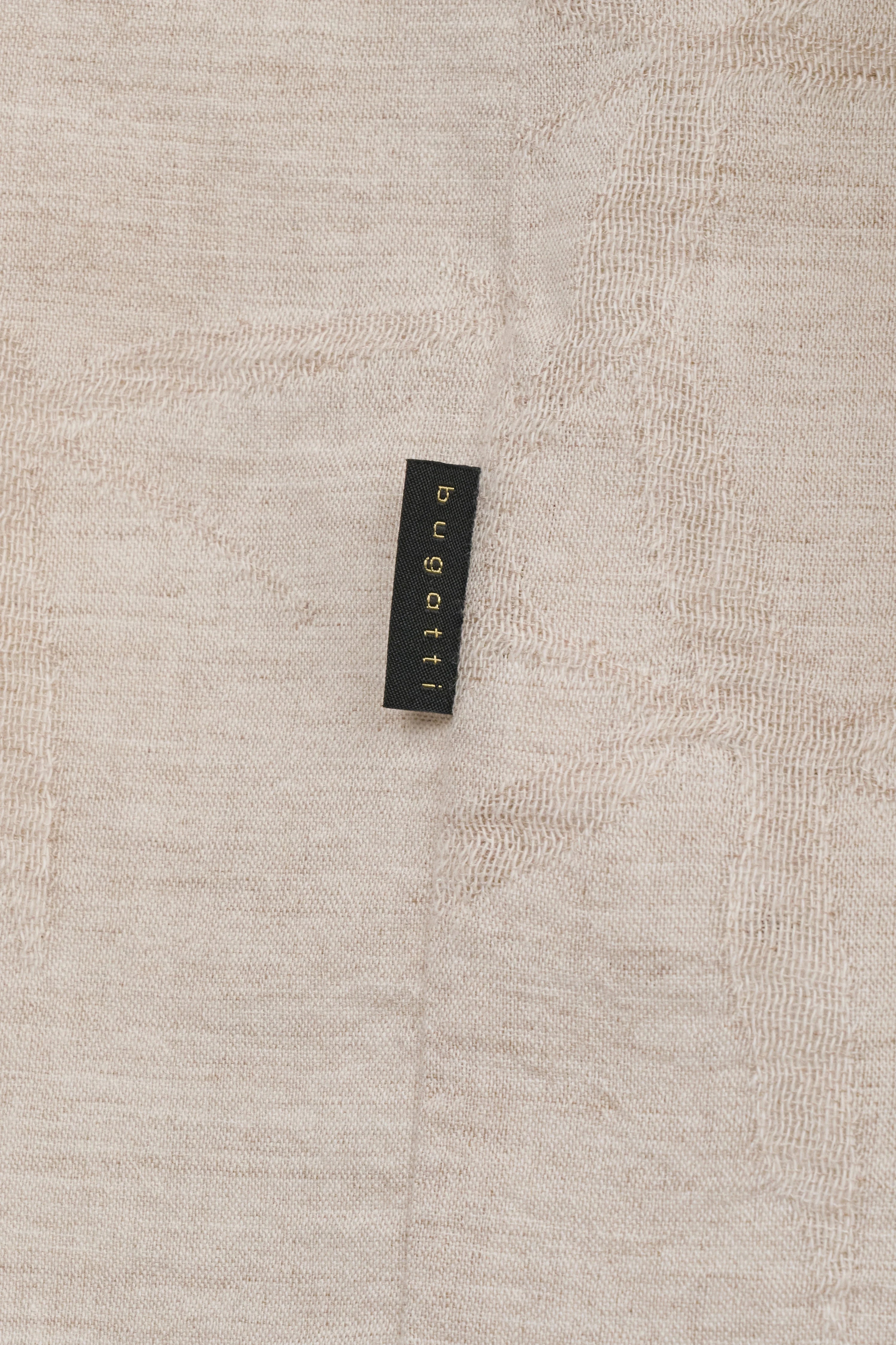 bugatti-etiket op beige stof met subtiele textuur en elegant design.