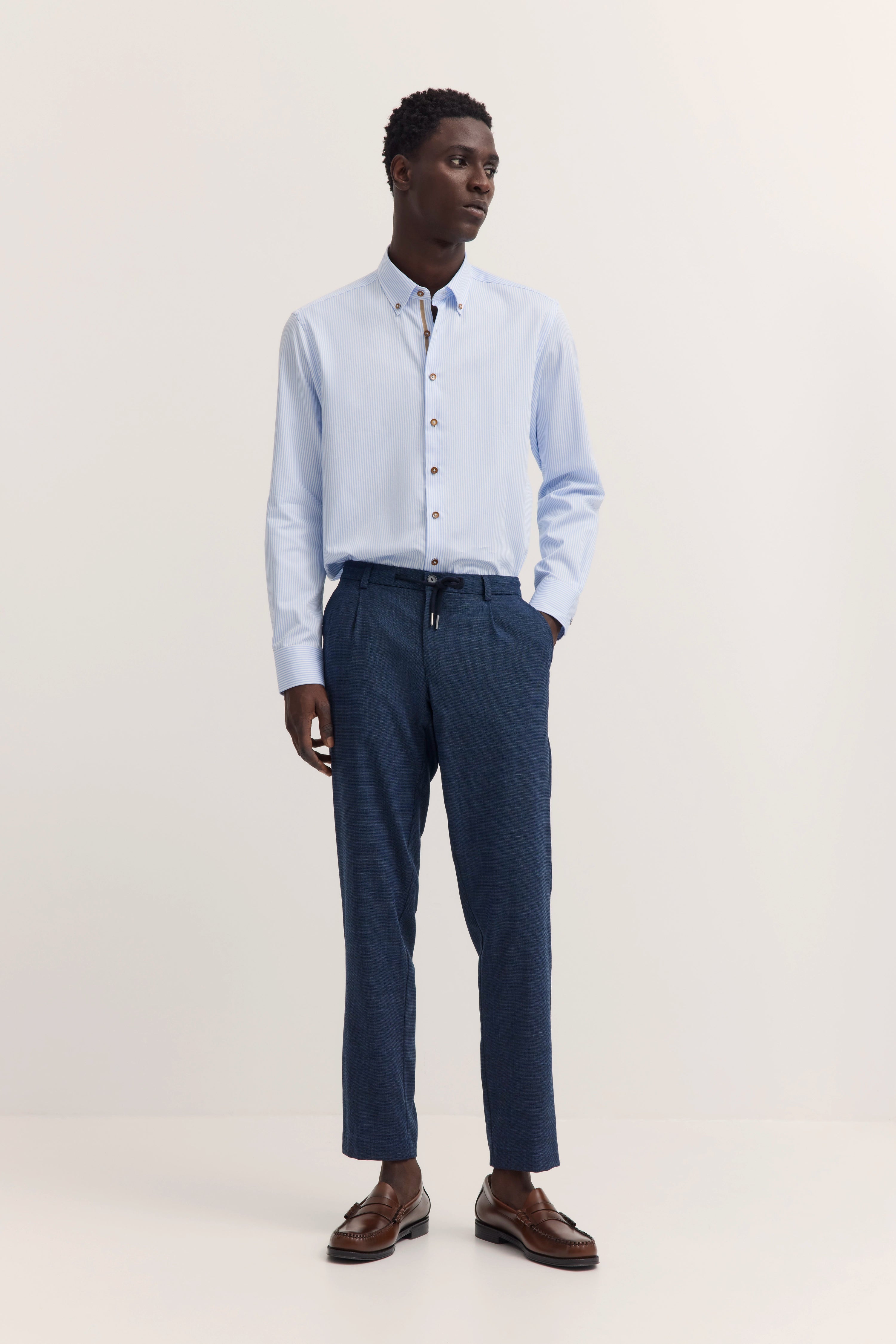 Model trägt hellblaues Hemd, dunkelblaue Hose