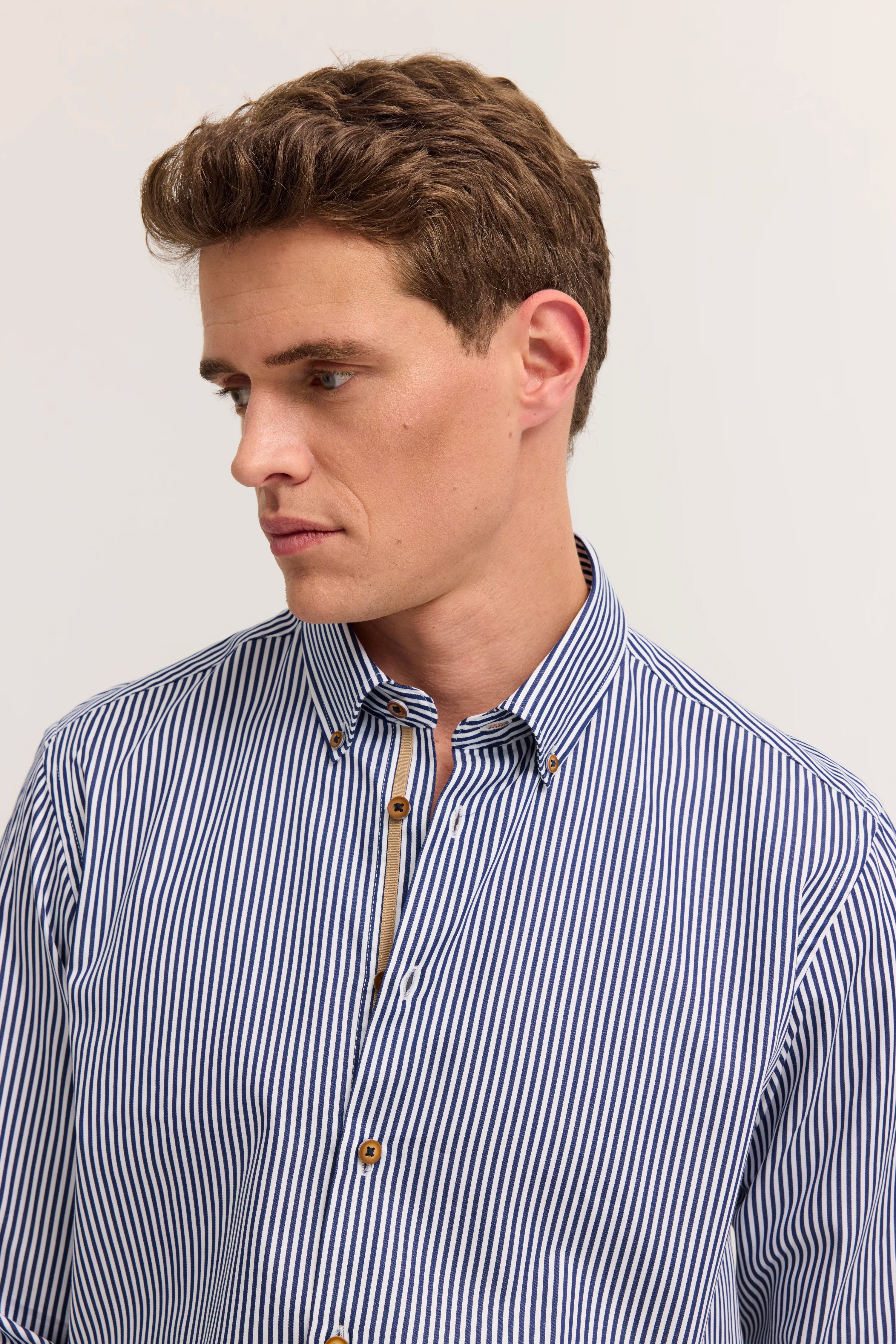 Modelbild, blau-weiß gestreiftes Hemd von bugatti, legeres Posing, seitliche Ansicht.