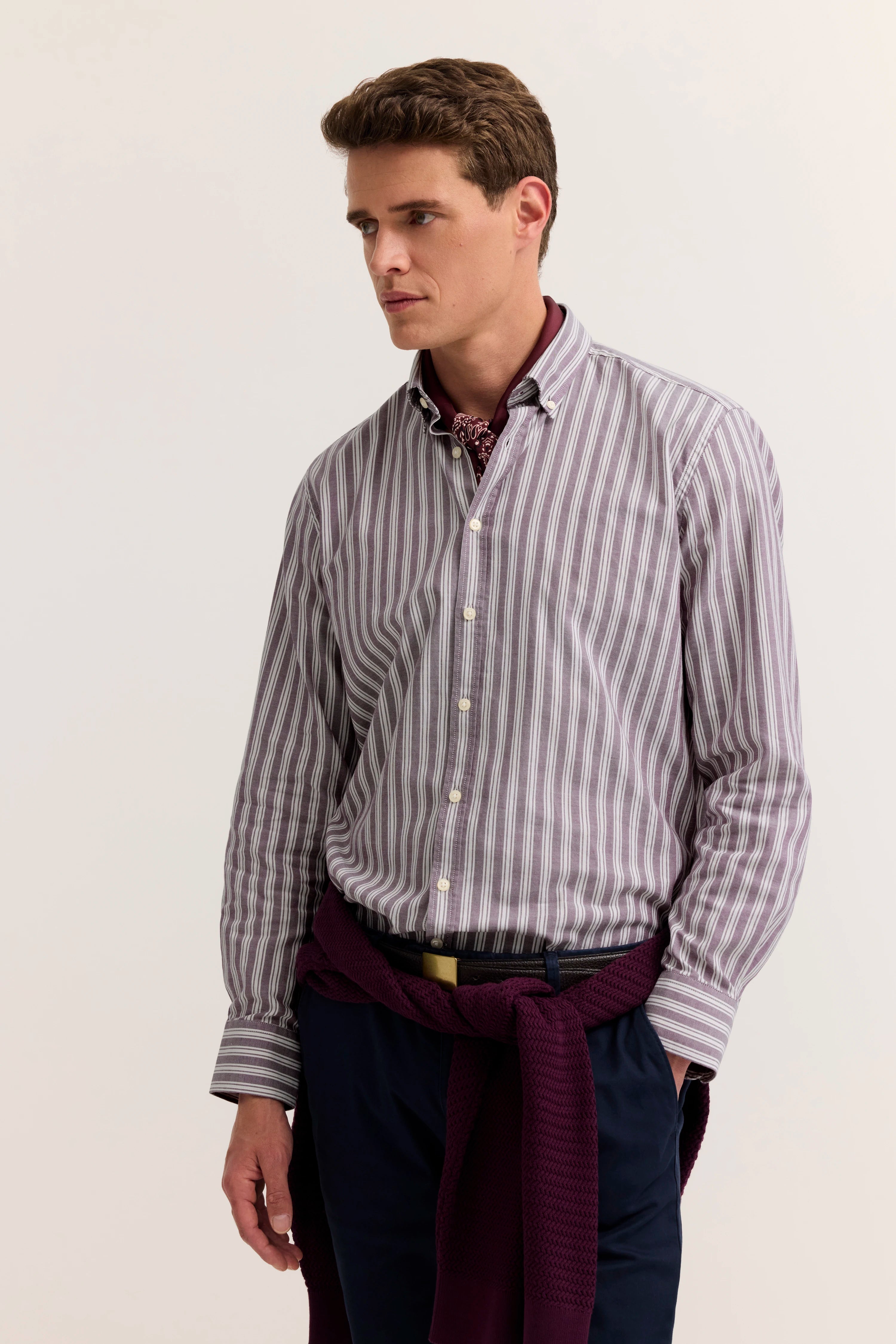 Gestreiftes Hemd, weinroter Schal, marineblaue Hose. Modelbild, entspannte Pose. bugatti Stil.