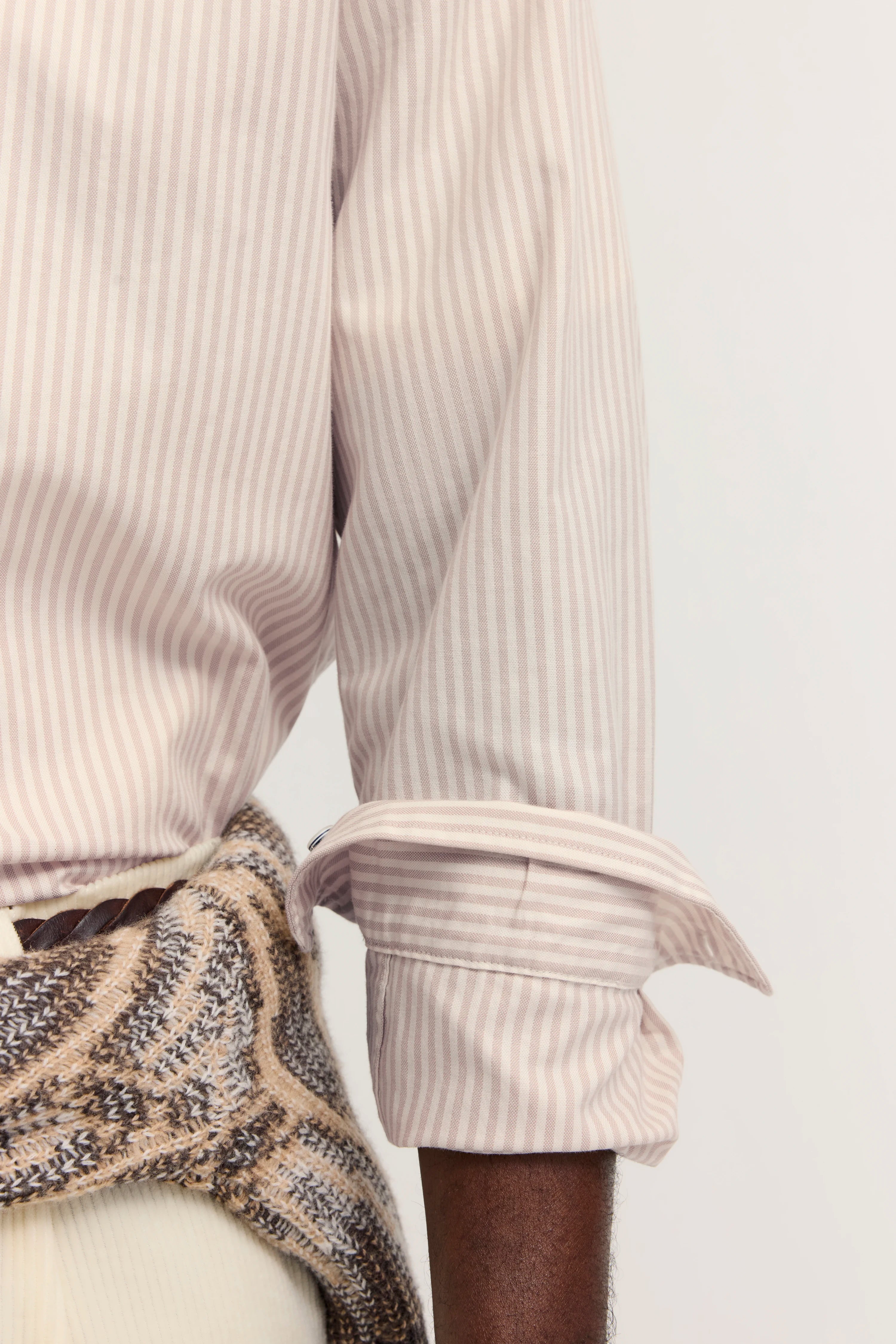 Gestreiftes Hemd in Pastell, leger gebunden mit Strickmuster-Pullover. Detailaufnahme.
