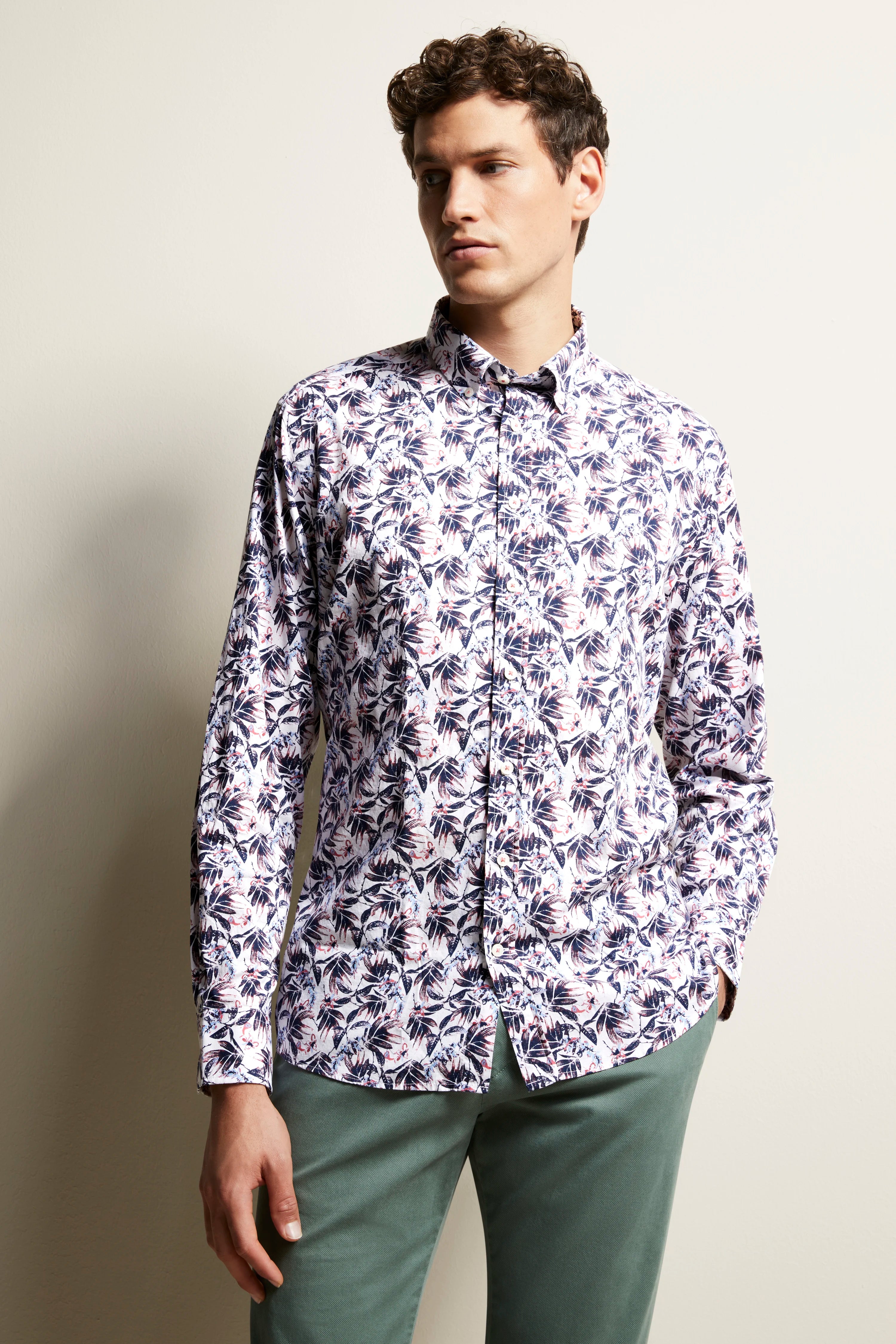 Model draagt wit-blauw bloemenhemd van bugatti, casual met groene broek. Halfportret.