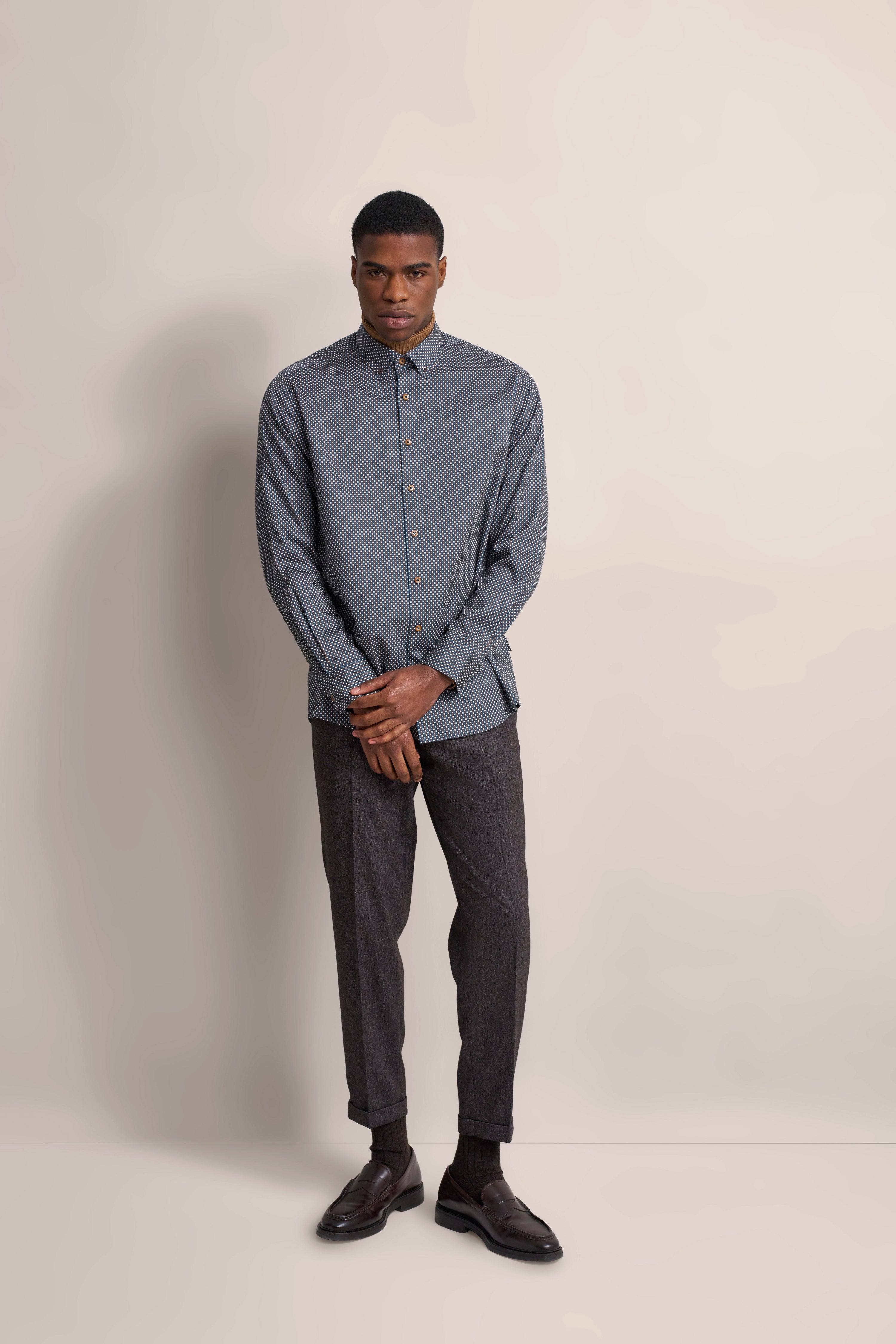 Model in grauem Musterhemd und dunkelgrauer Hose, lässige Pose, bugatti Stil und Eleganz.