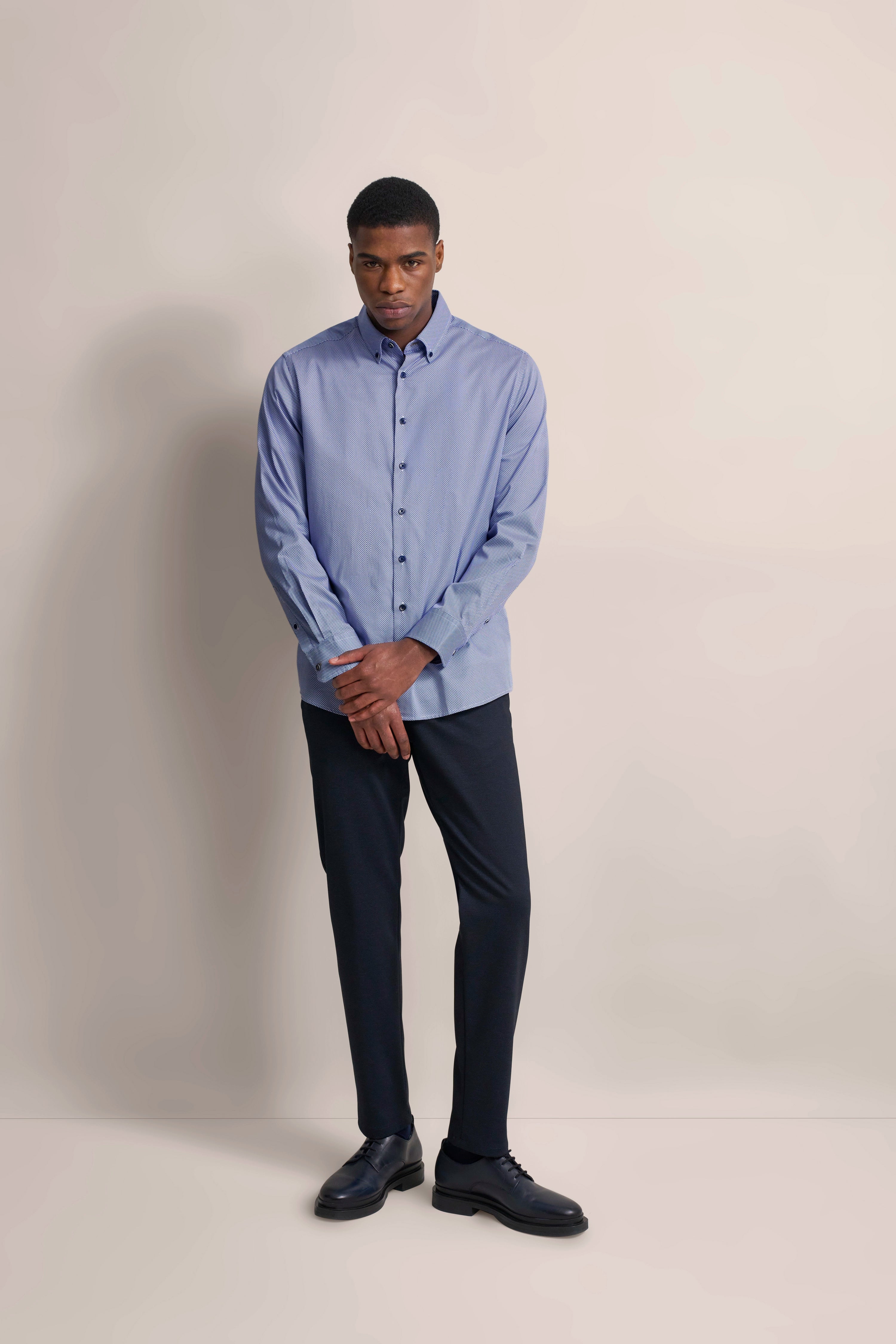 Model in hellblauem Hemd und dunkler Hose von bugatti, legeres Posing, zeitloser Stil.