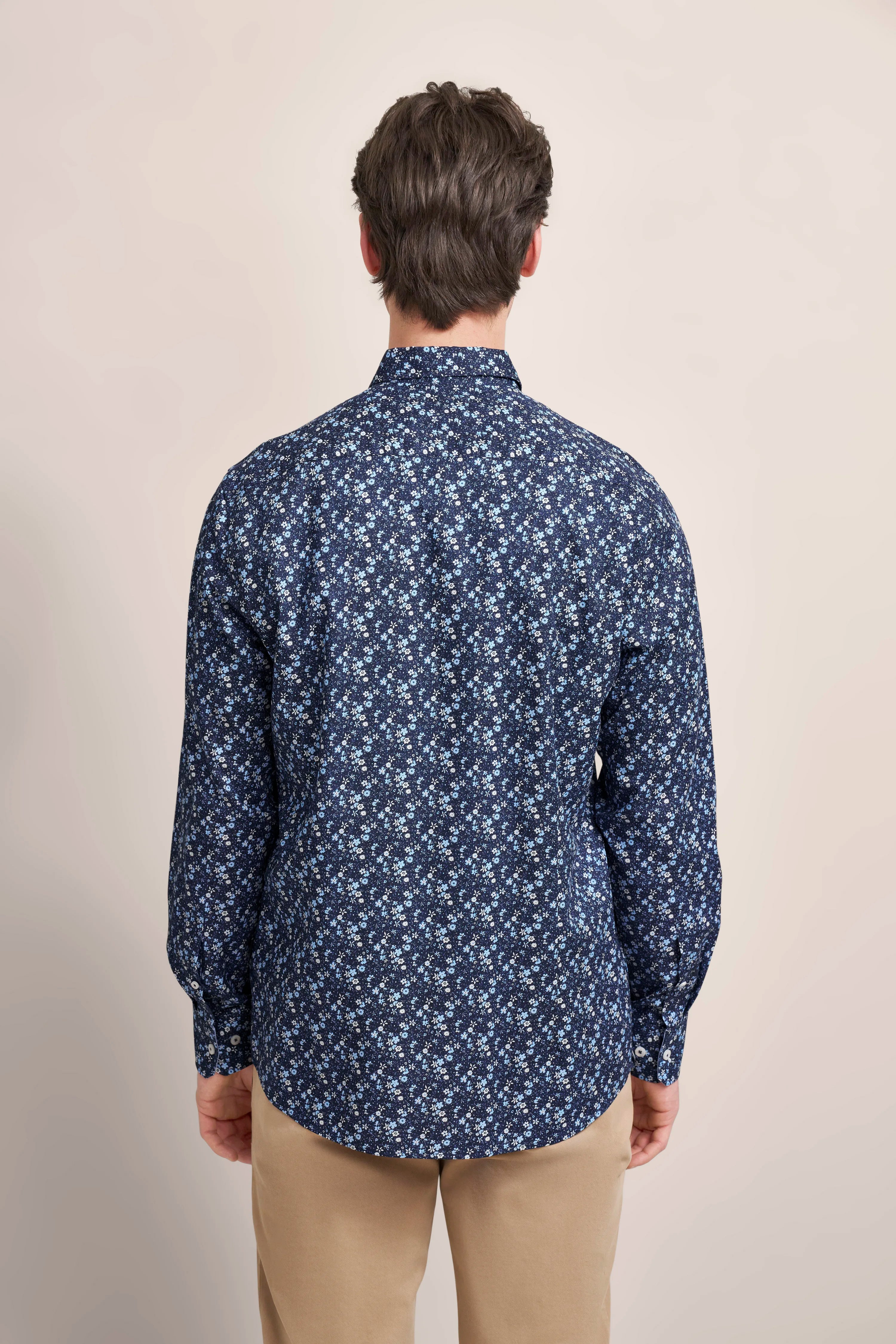 Herrenmodell von hinten in floralem, blauem bugatti-Hemd und beiger Hose, legerer Look.