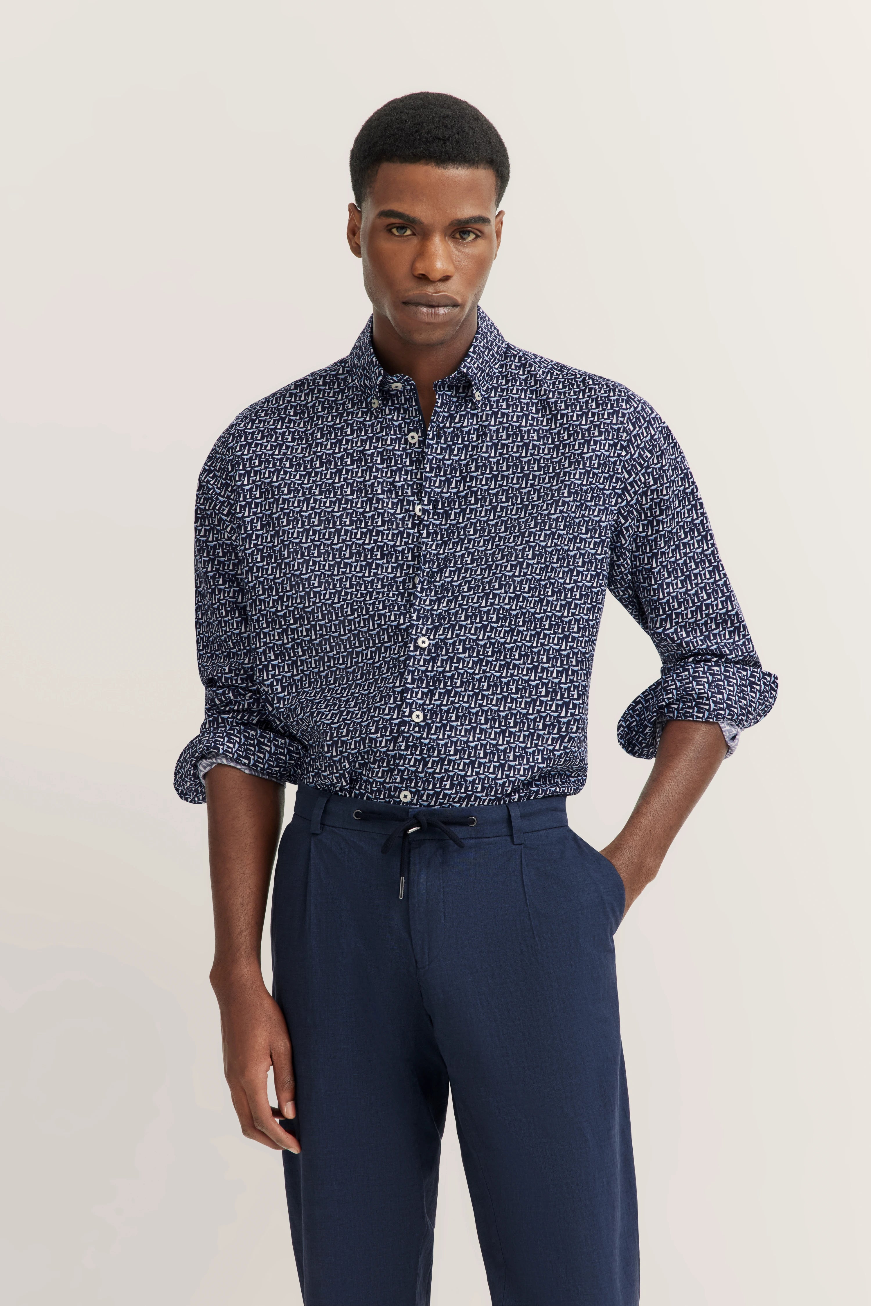 bugatti model, man in blauw patroonhemd, blauwe broek, ontspannen pose, Italiaanse inspiratie en stijl.
