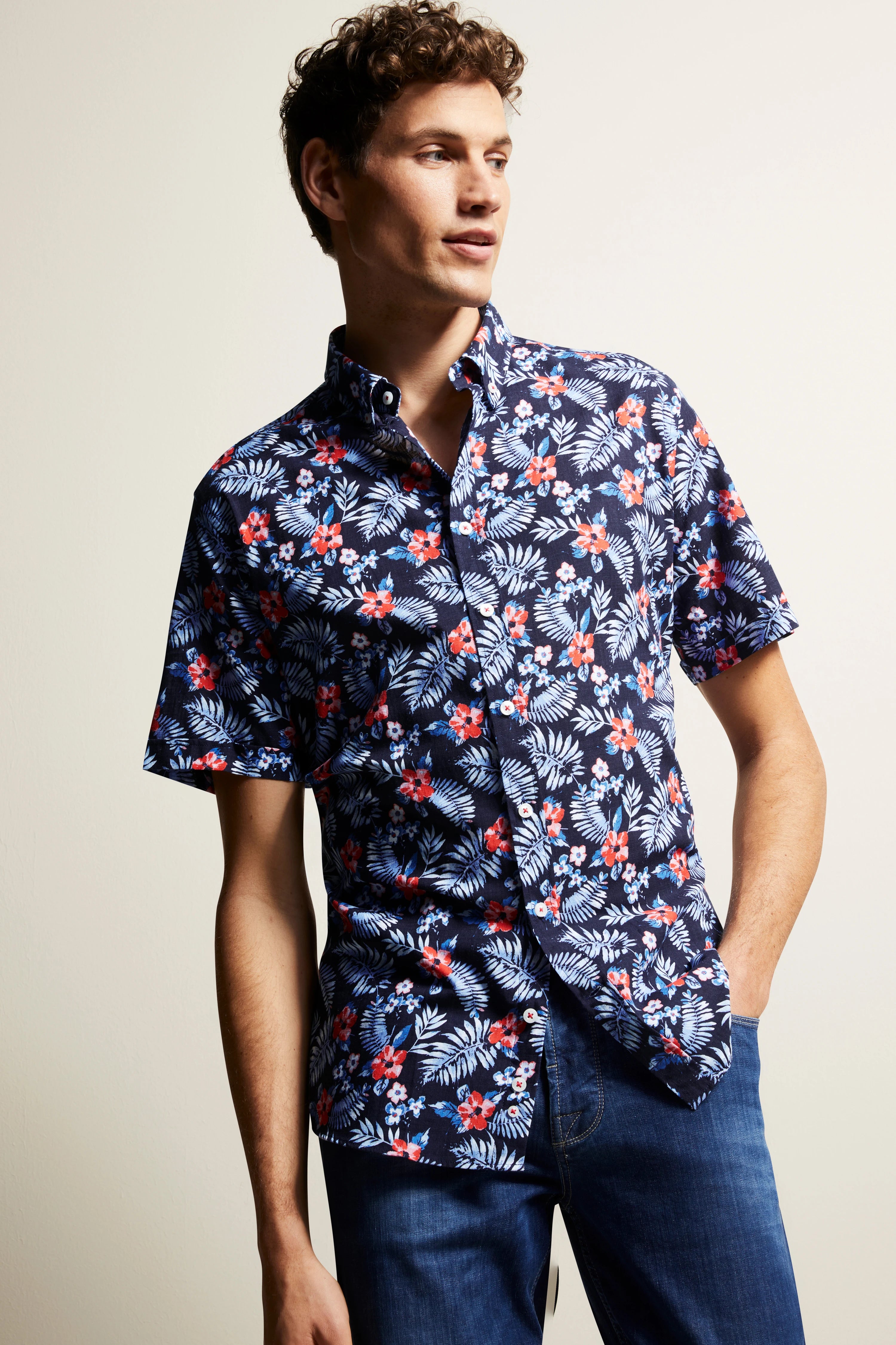 bugatti overhemd, blauw met bloemenpatroon, casual modelpose, hand in broekzak, stijlvol en ontspannen.