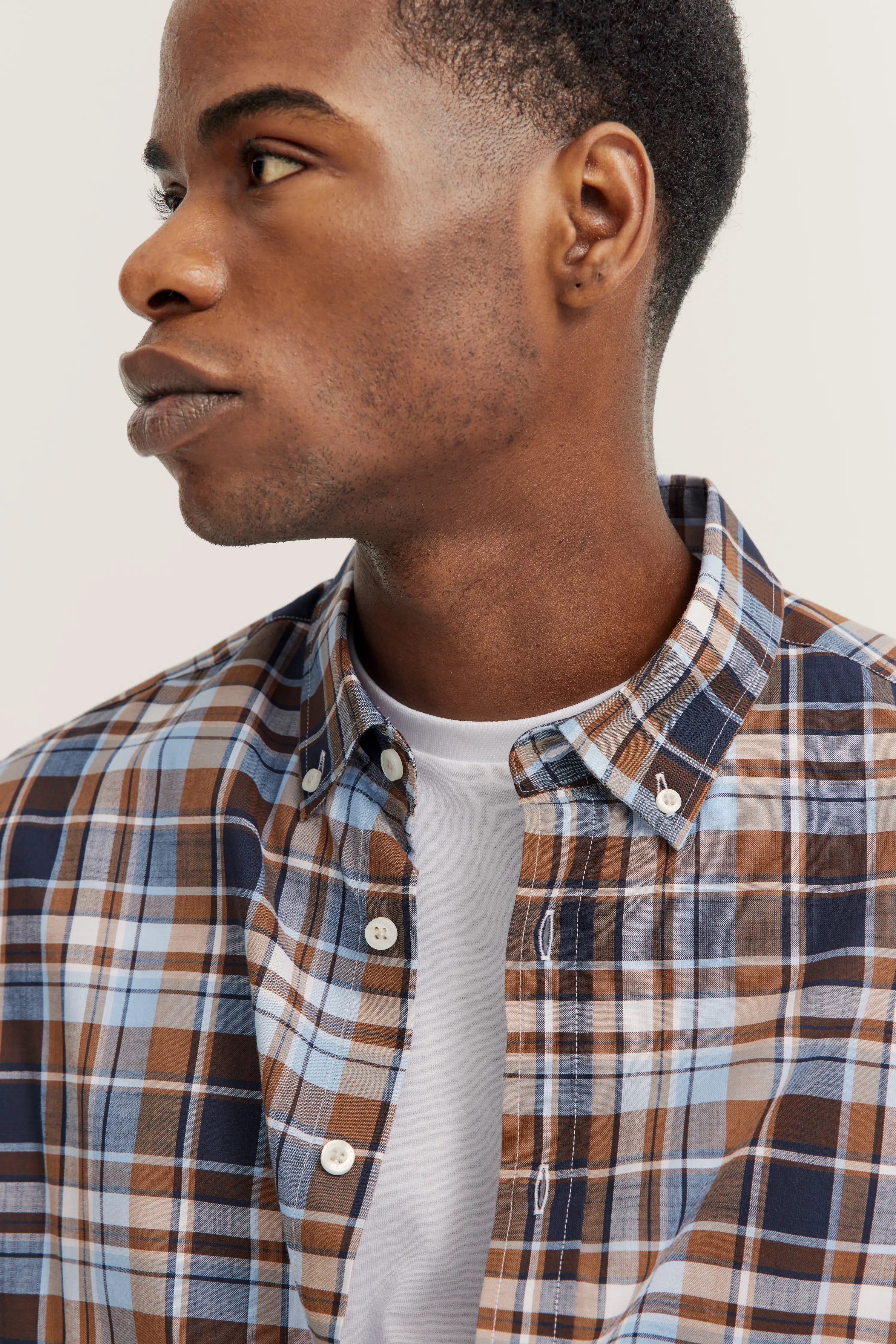 Geruit bugatti-overhemd in blauw en bruin over wit T-shirt. Modelbeeld, zijwaarts poseren.