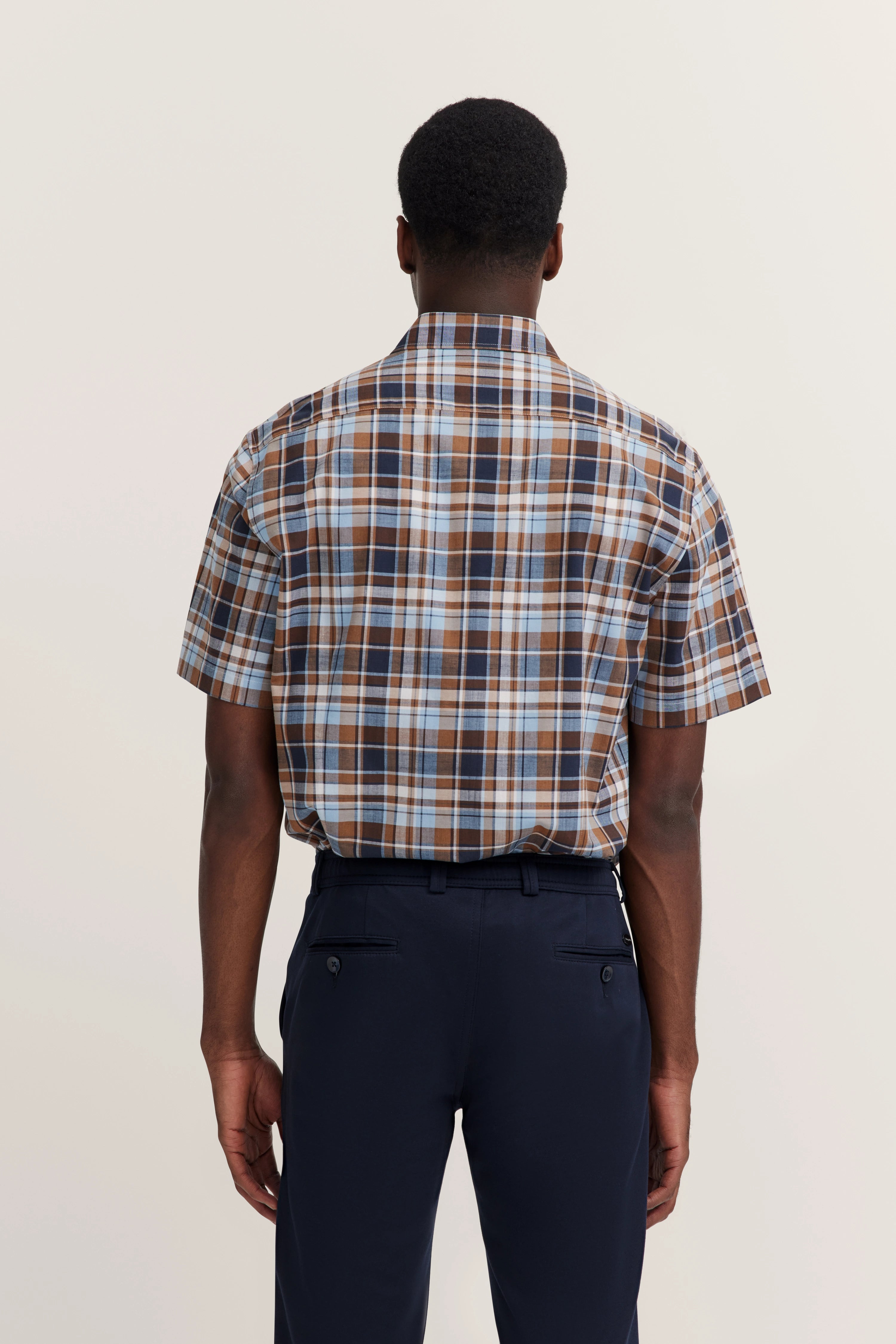 Geruit kortemouwenshirt in bruin en blauw, model van achteren, ontspannen pose.