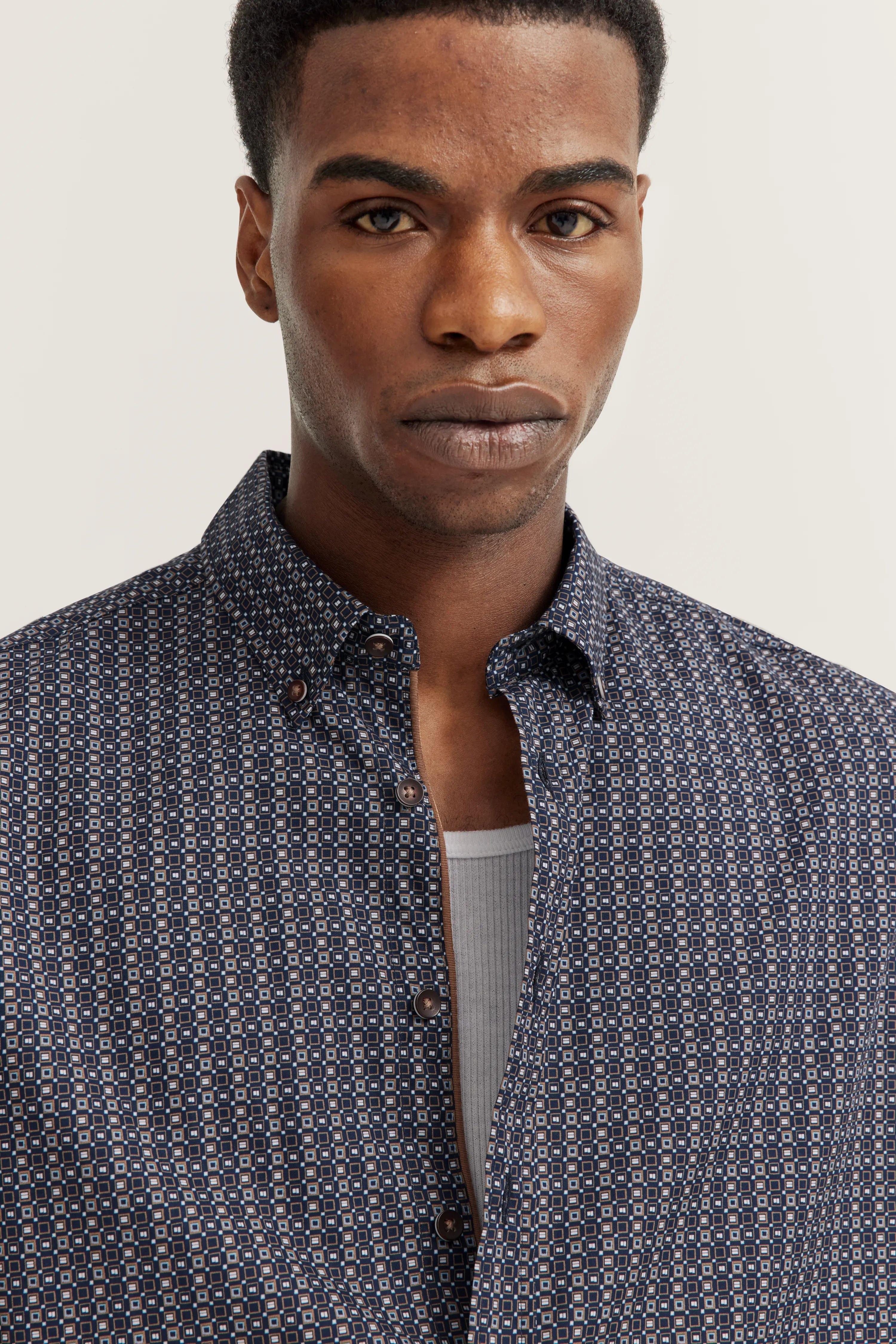 Borstbeeld met blauw patroon overhemd en wit shirt eronder.