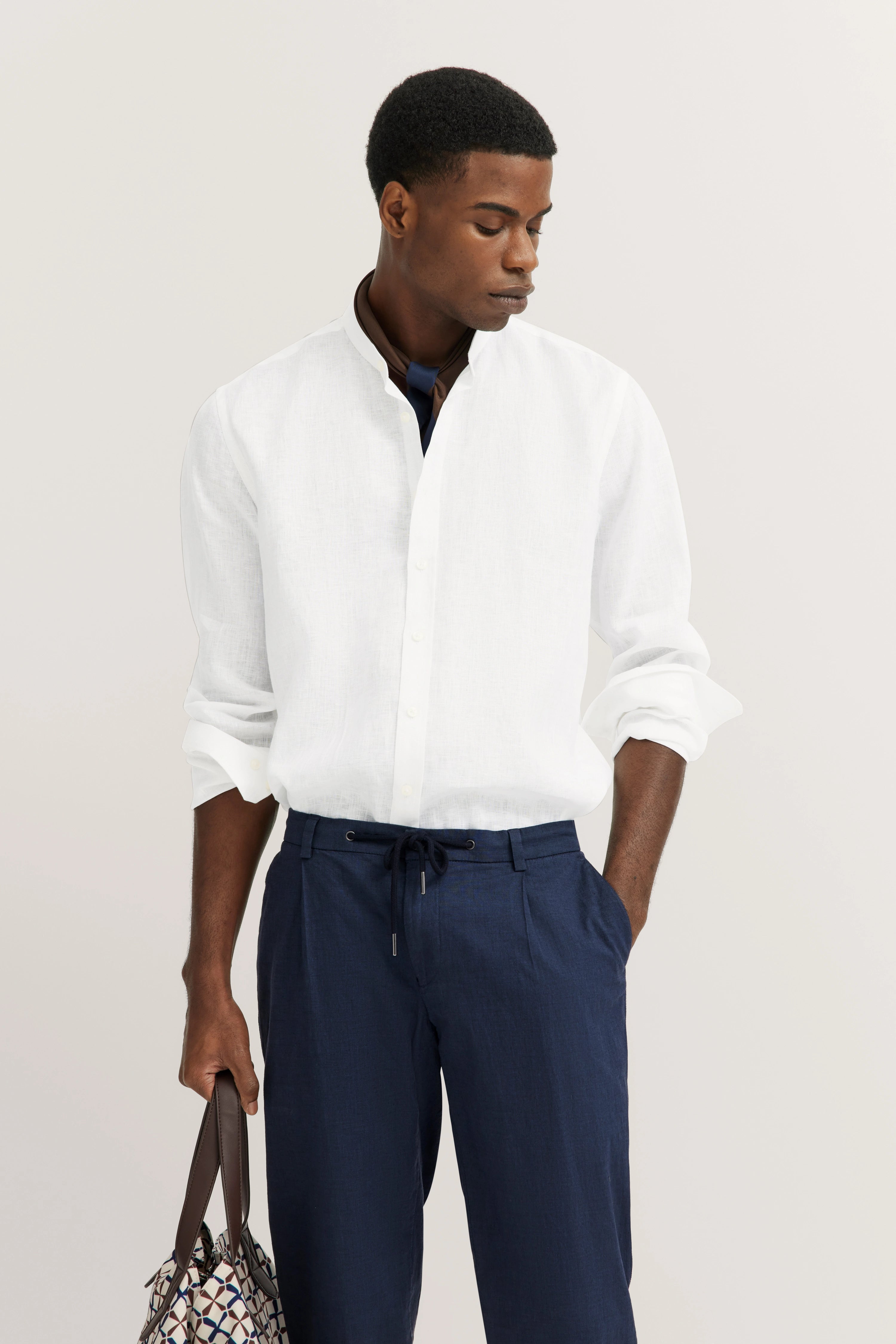 bugatti modelafbeelding: Wit overhemd, blauwe broek, tas, ontspannen pose, stijlvol en tijdloos.