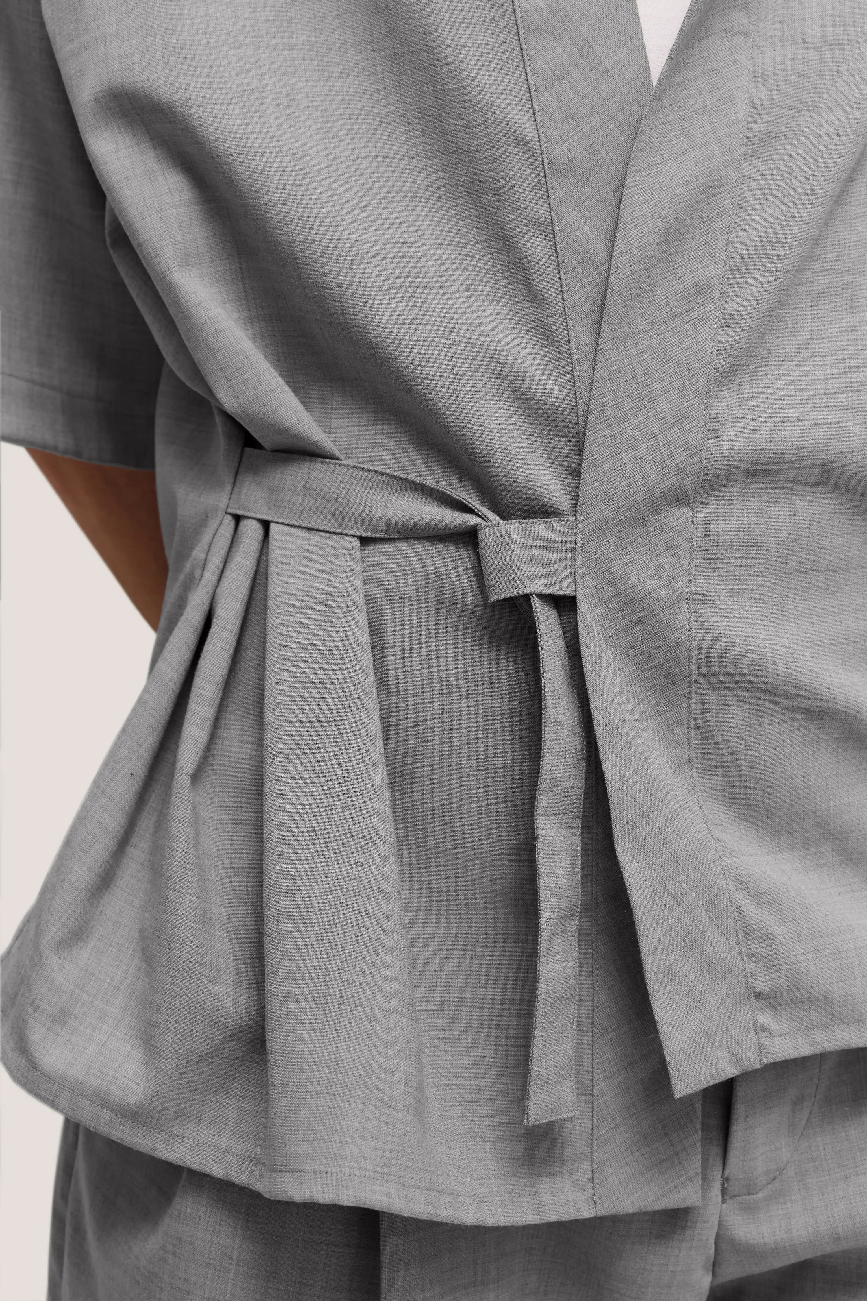 Graues, kariertes Oberteil mit Taillengürtel, Detailaufnahme, bugatti Stil.