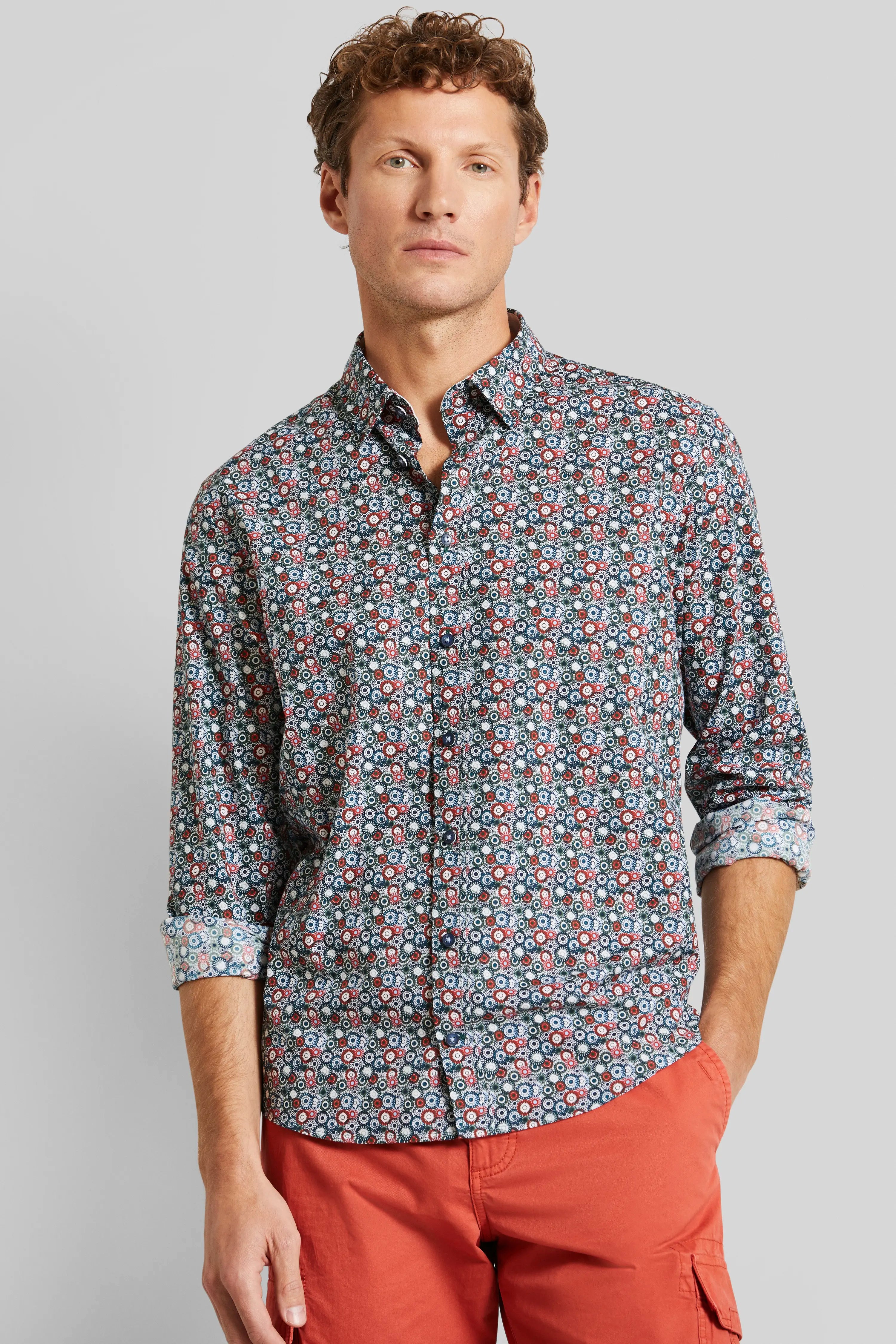 Man in een geruit overhemd met rode shorts, casual modelbeeld, ontspannen pose.