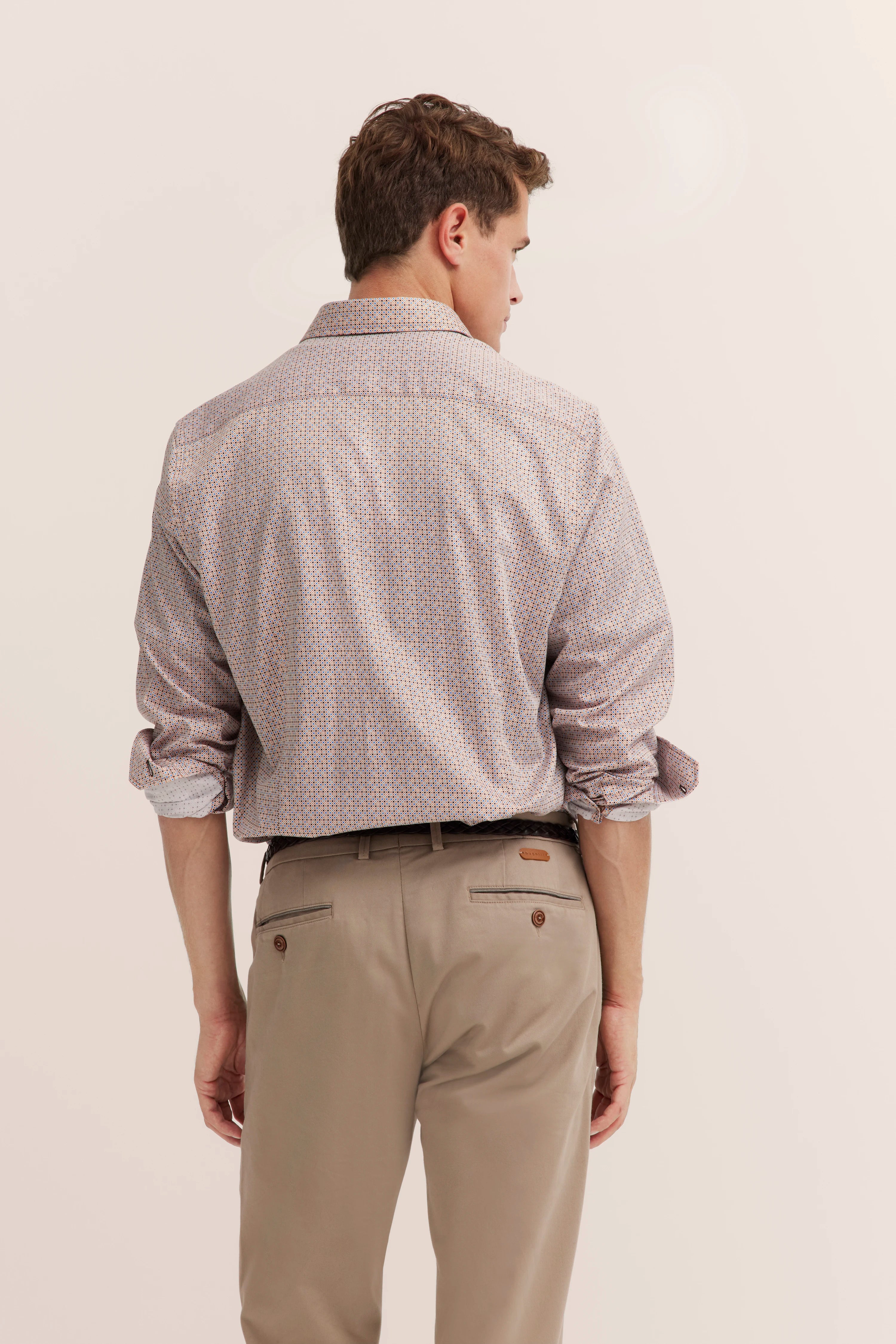 Rückansicht Model in gemustertem Hemd und beige Chinos, lockere Pose.