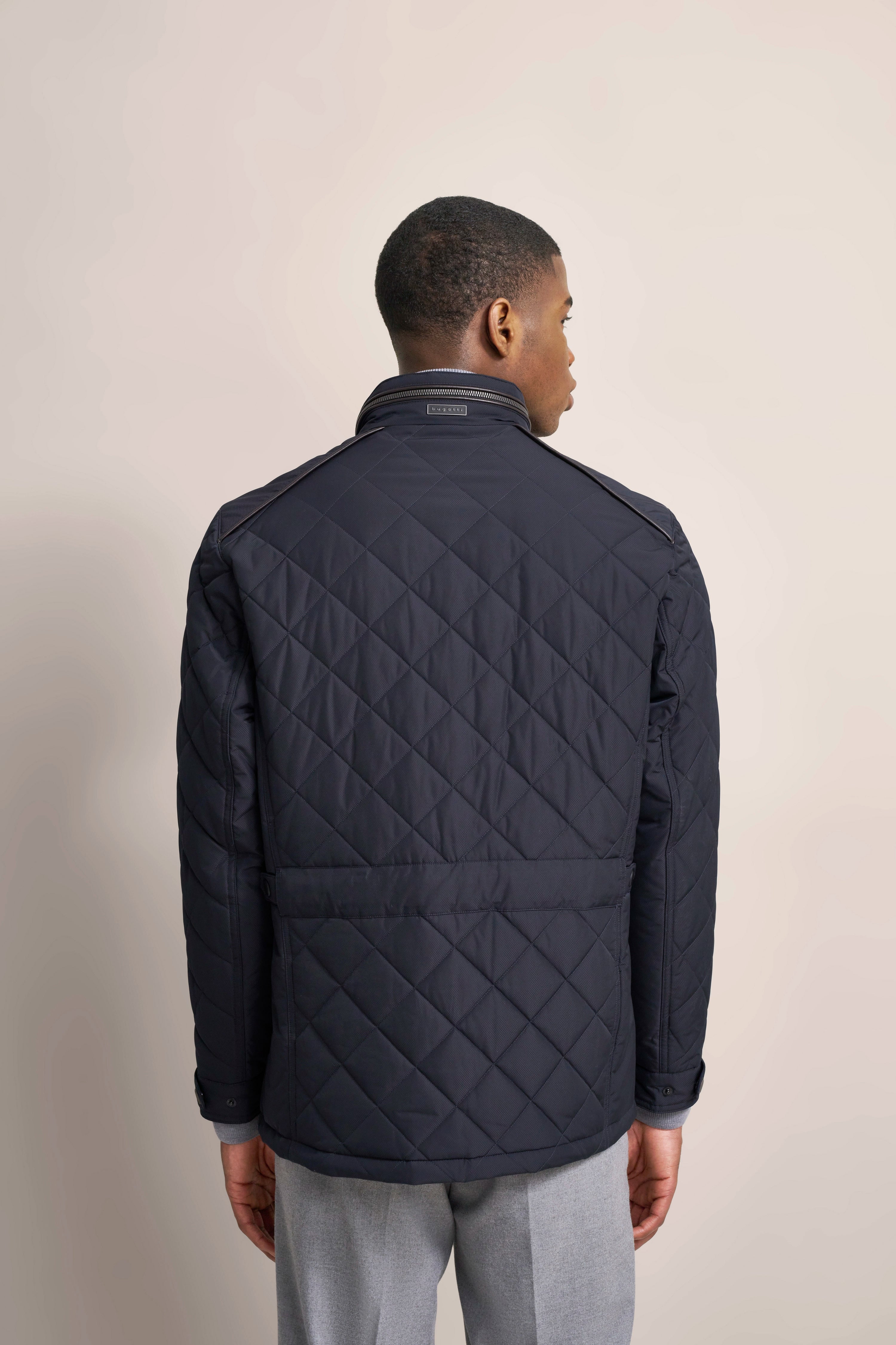 bugatti Steppjacke in Dunkelblau, Model von hinten, graue Hose.