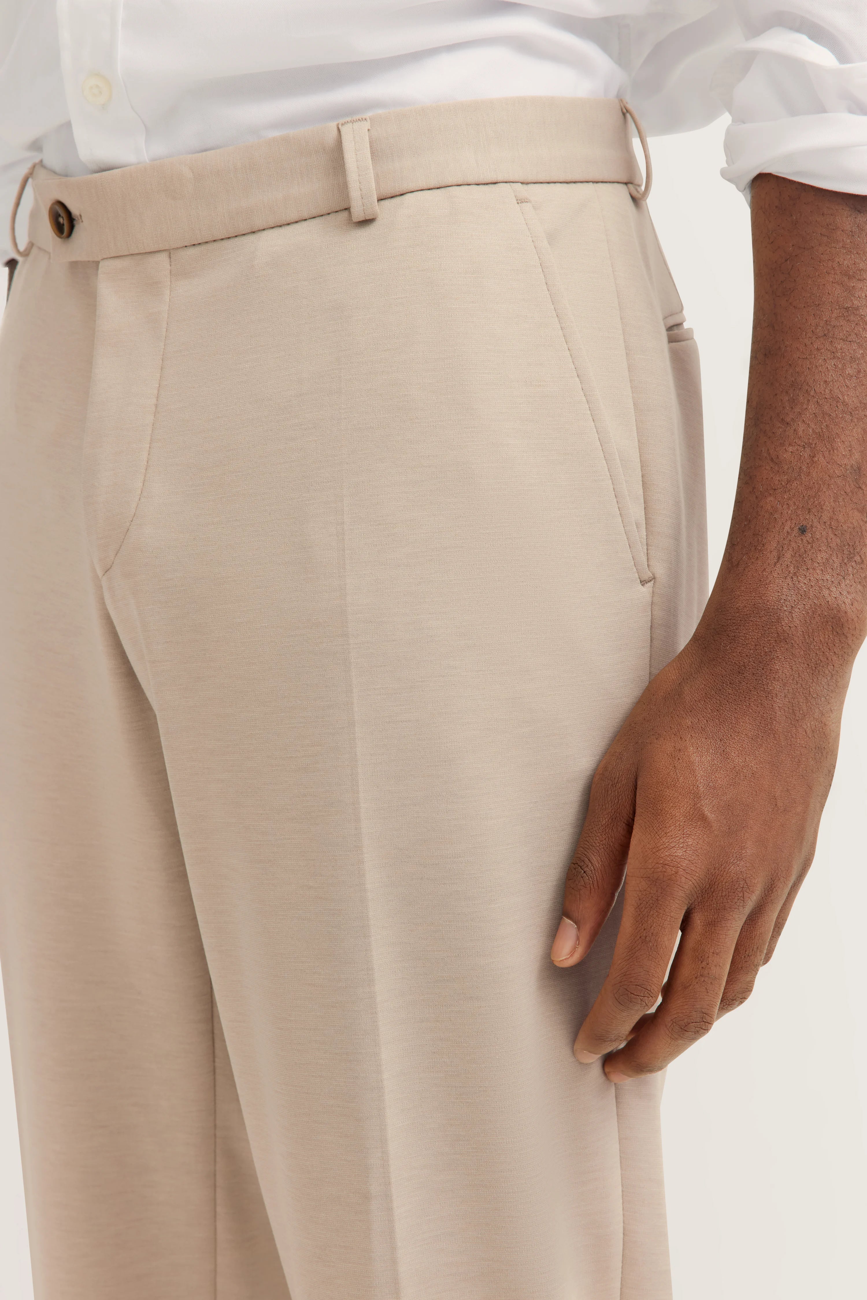 Weißes Hemd, beige Hose, braune Schuhe, Modelbild, lässige Pose, bugatti Stil.