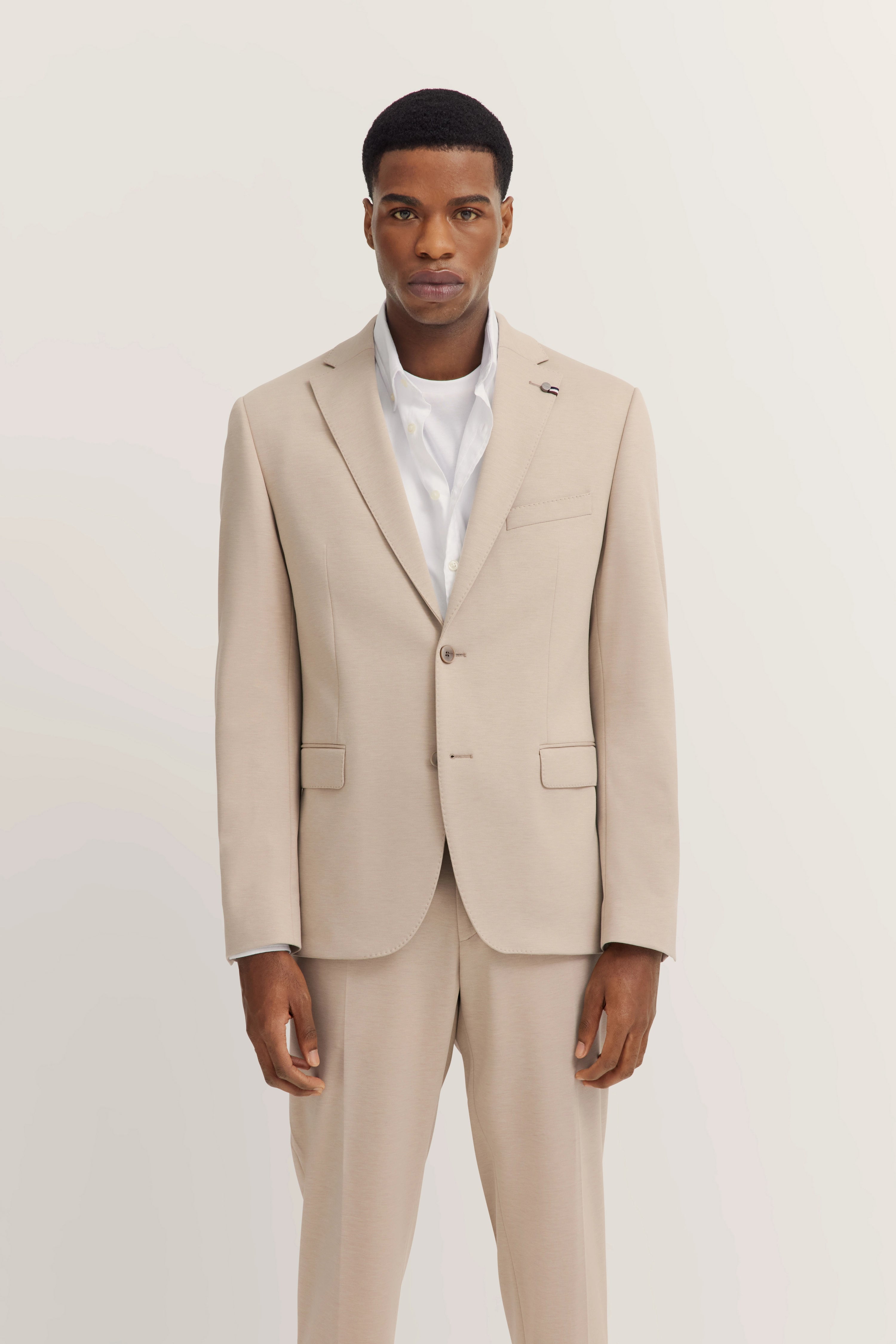 Beiges bugatti Anzug-Set mit weißem Hemd, Modelbild, elegantes Posing.