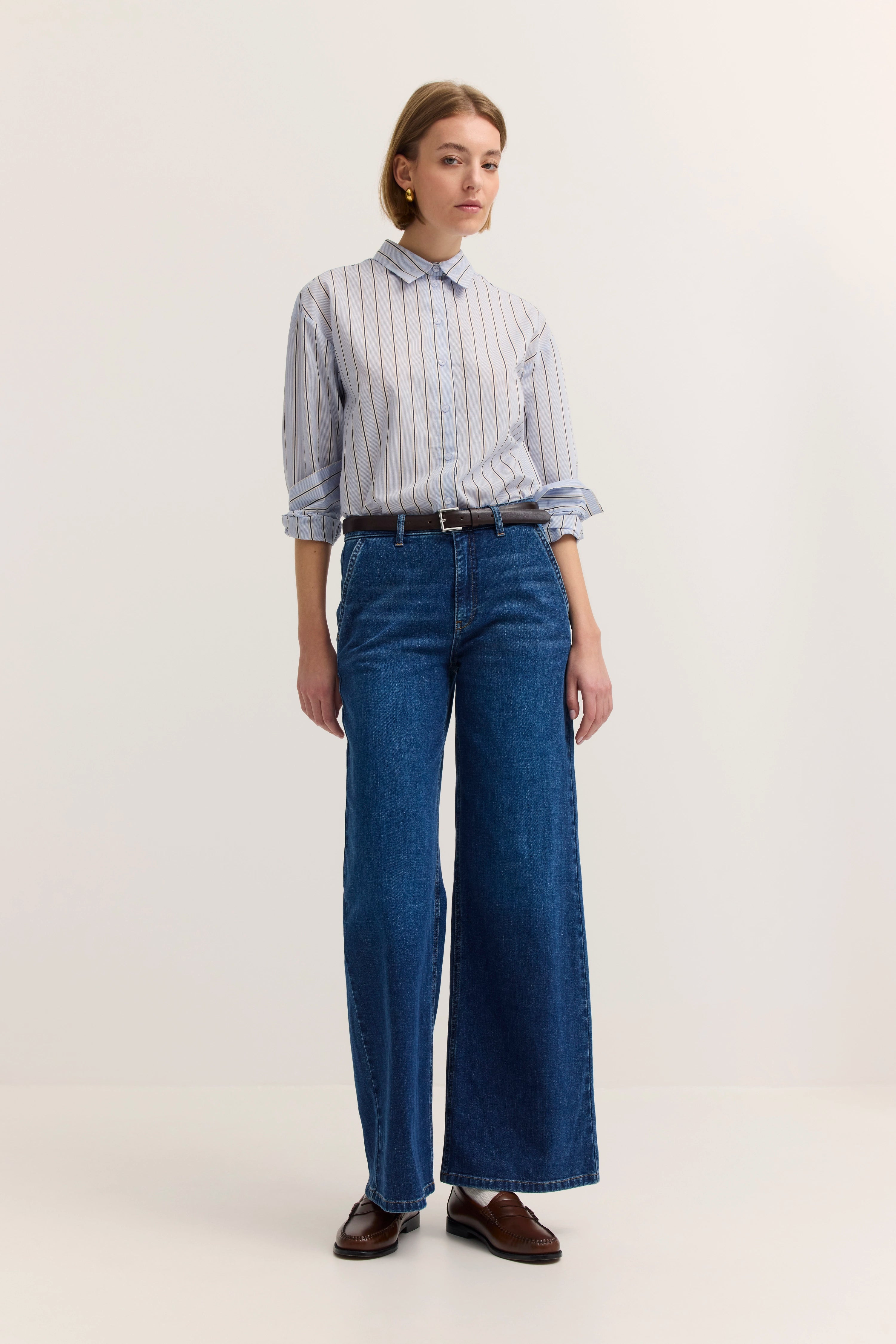 Streifenbluse und blaue Jeans im Modelbild, entspannt stehend.