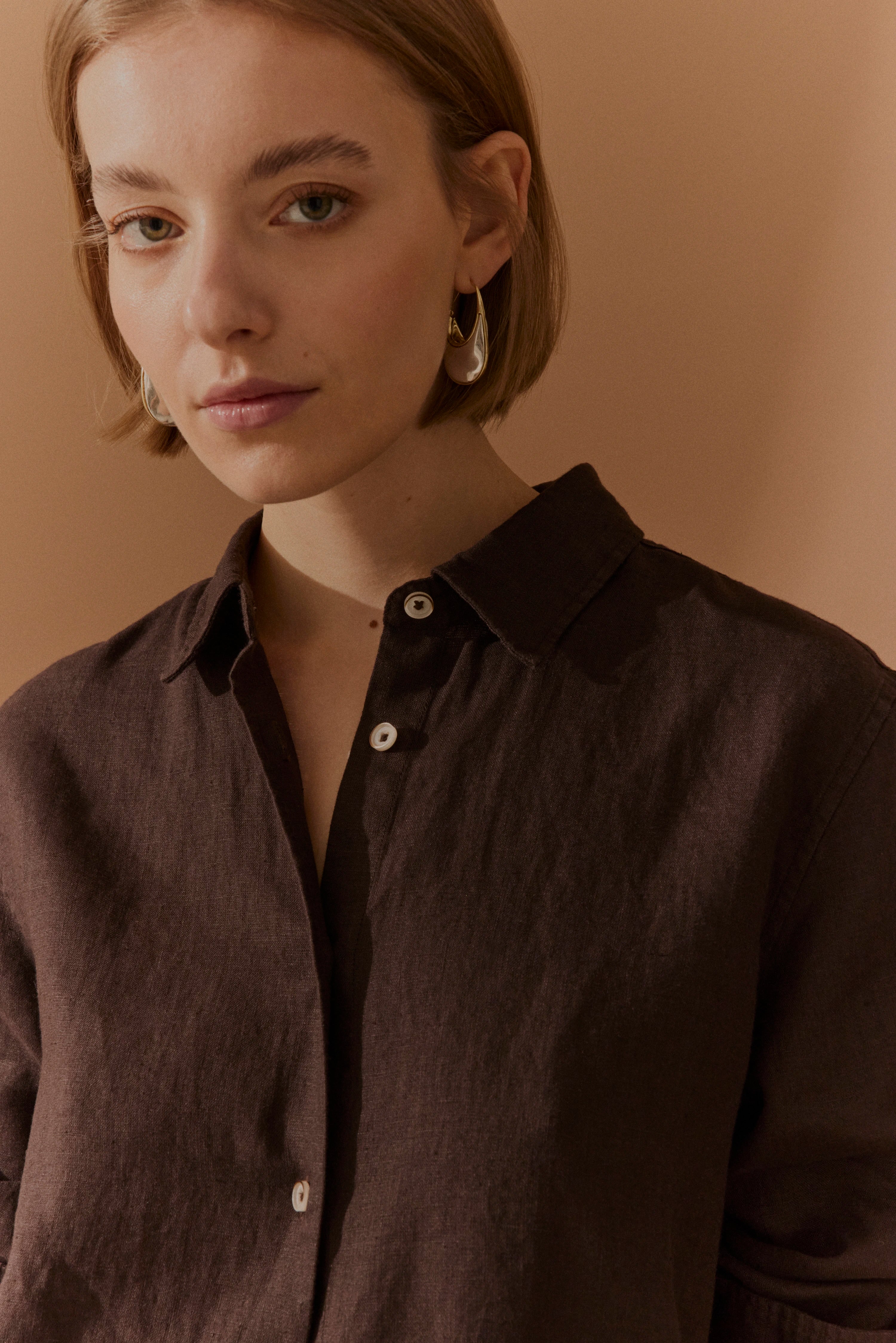 Büste eines Models in brauner bugatti Bluse vor beigem Hintergrund.