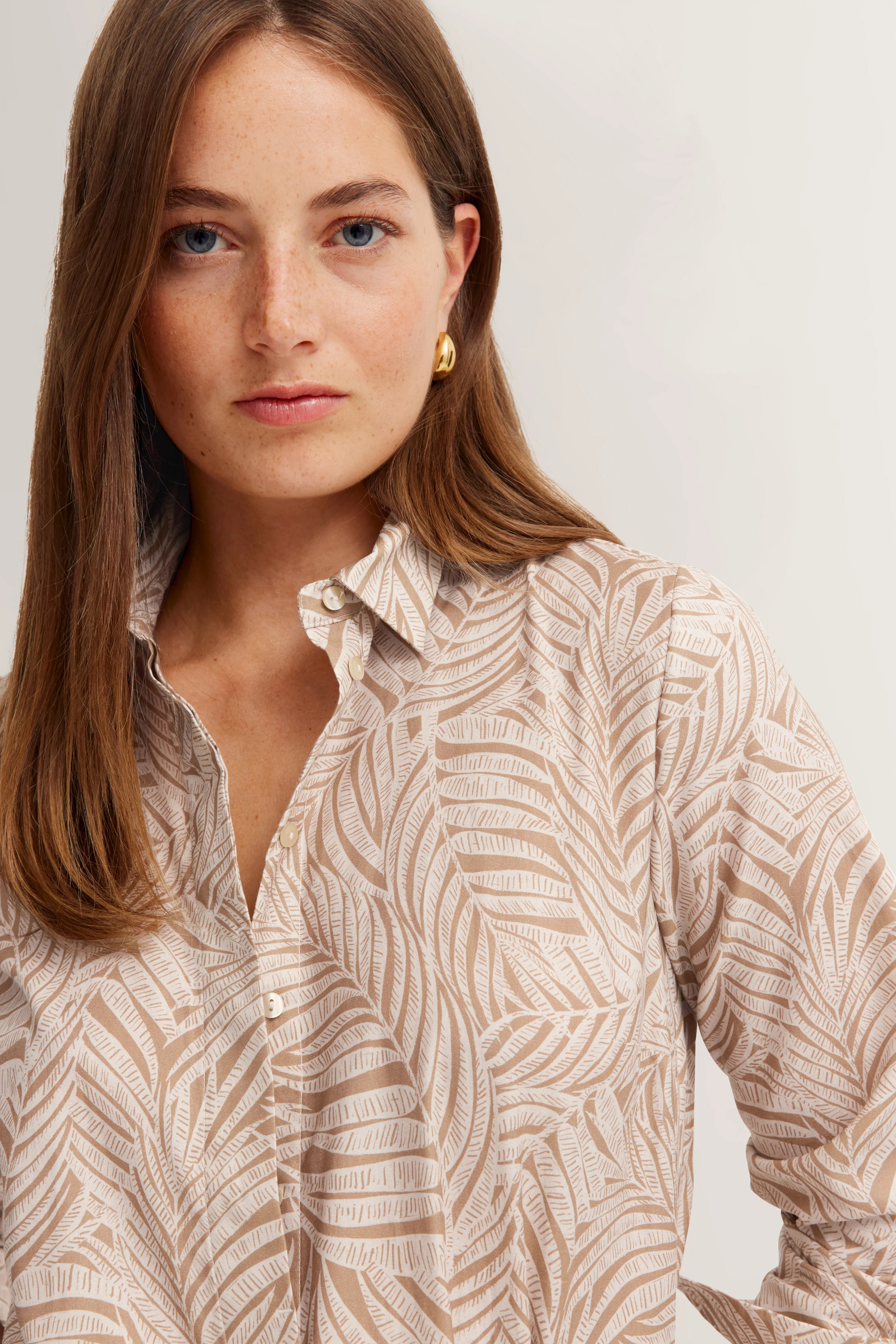 Damesblouse met beige-witte bladmuster, model aan voorzijde, bugatti stijl.