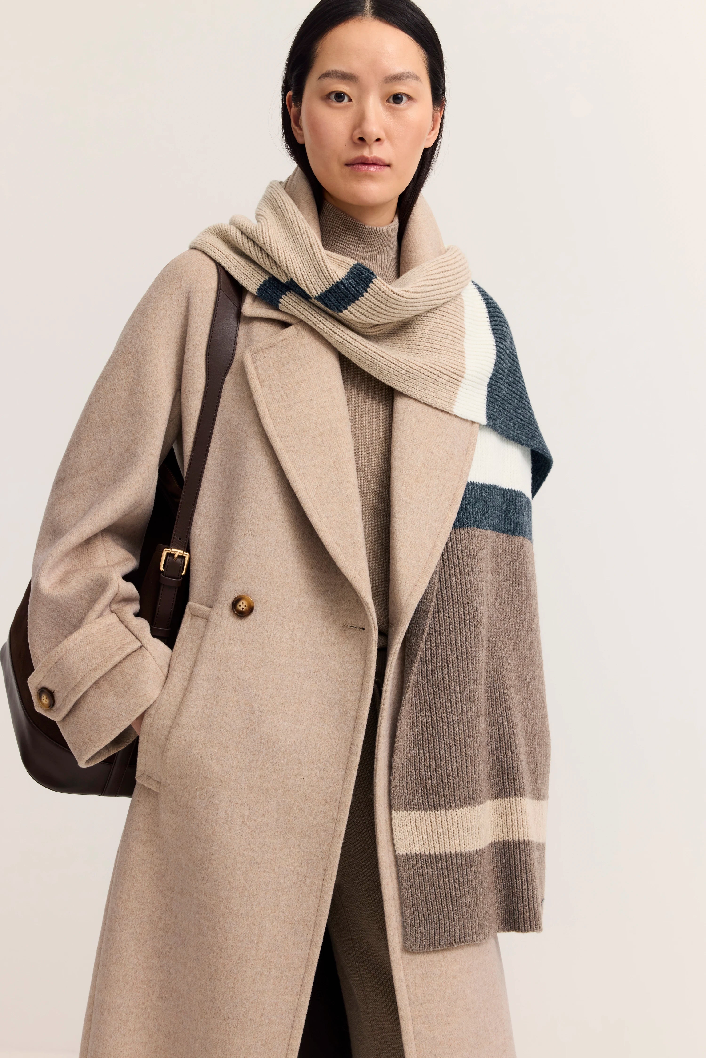 "bugatti Modelbild, beige Mantel, gestrickter Schal in beige-blau, legeres Posing, stilvoll und zeitlos."