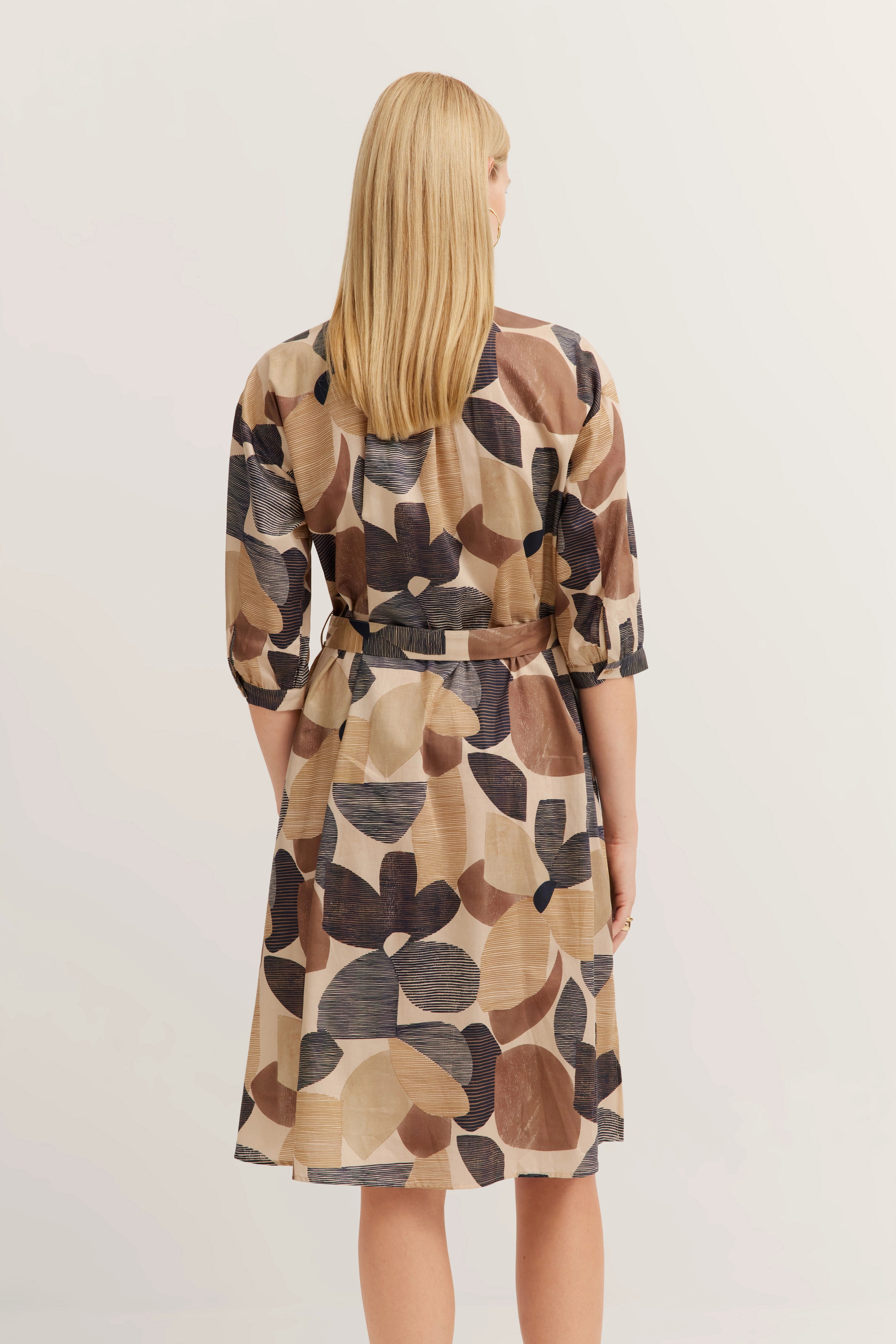 Kleid mit abstraktem Muster in Beige- und Brauntönen, Modell von hinten.