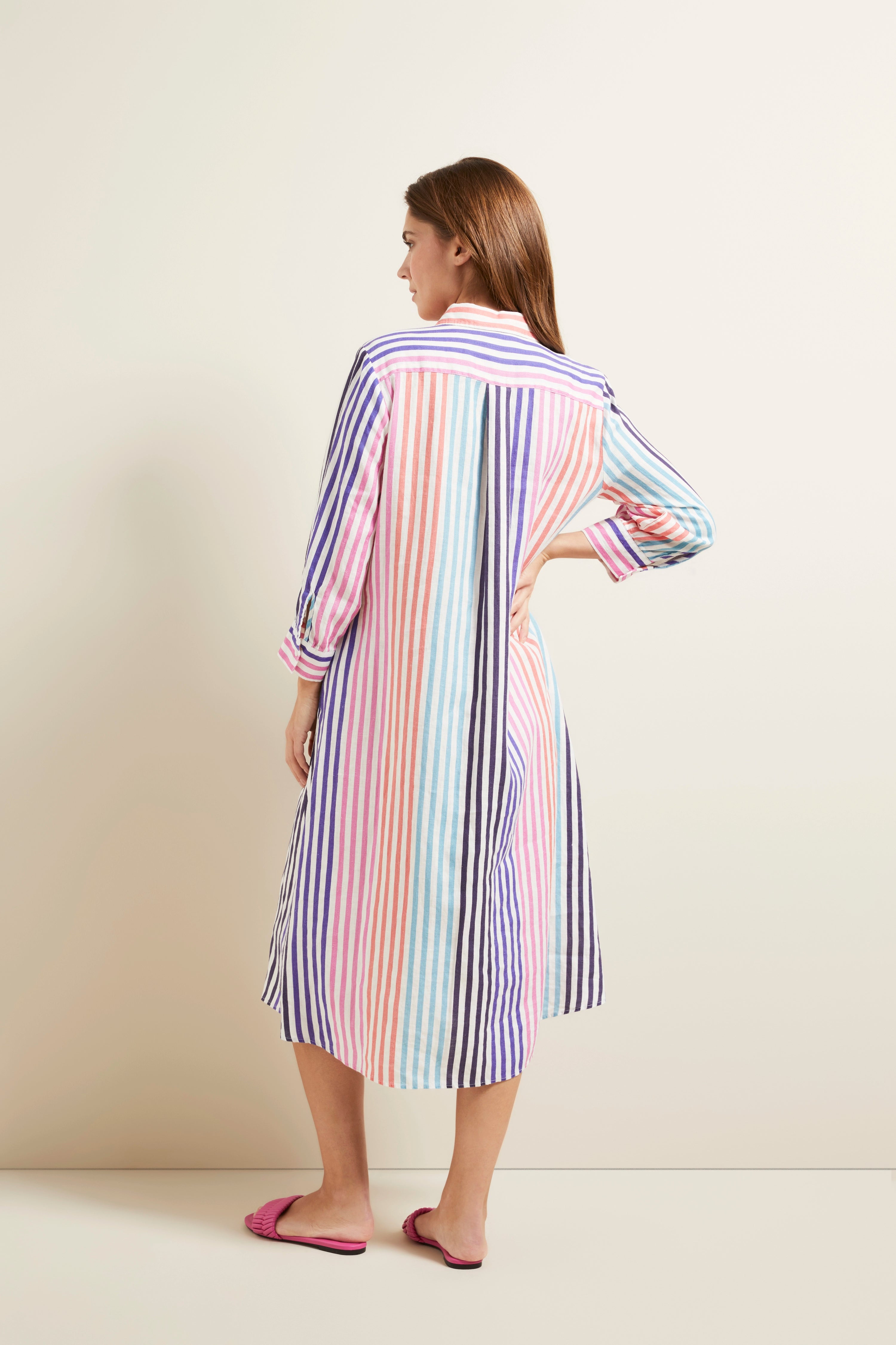 Model in colorful striped bugatti dress, back view, relaxed pose.