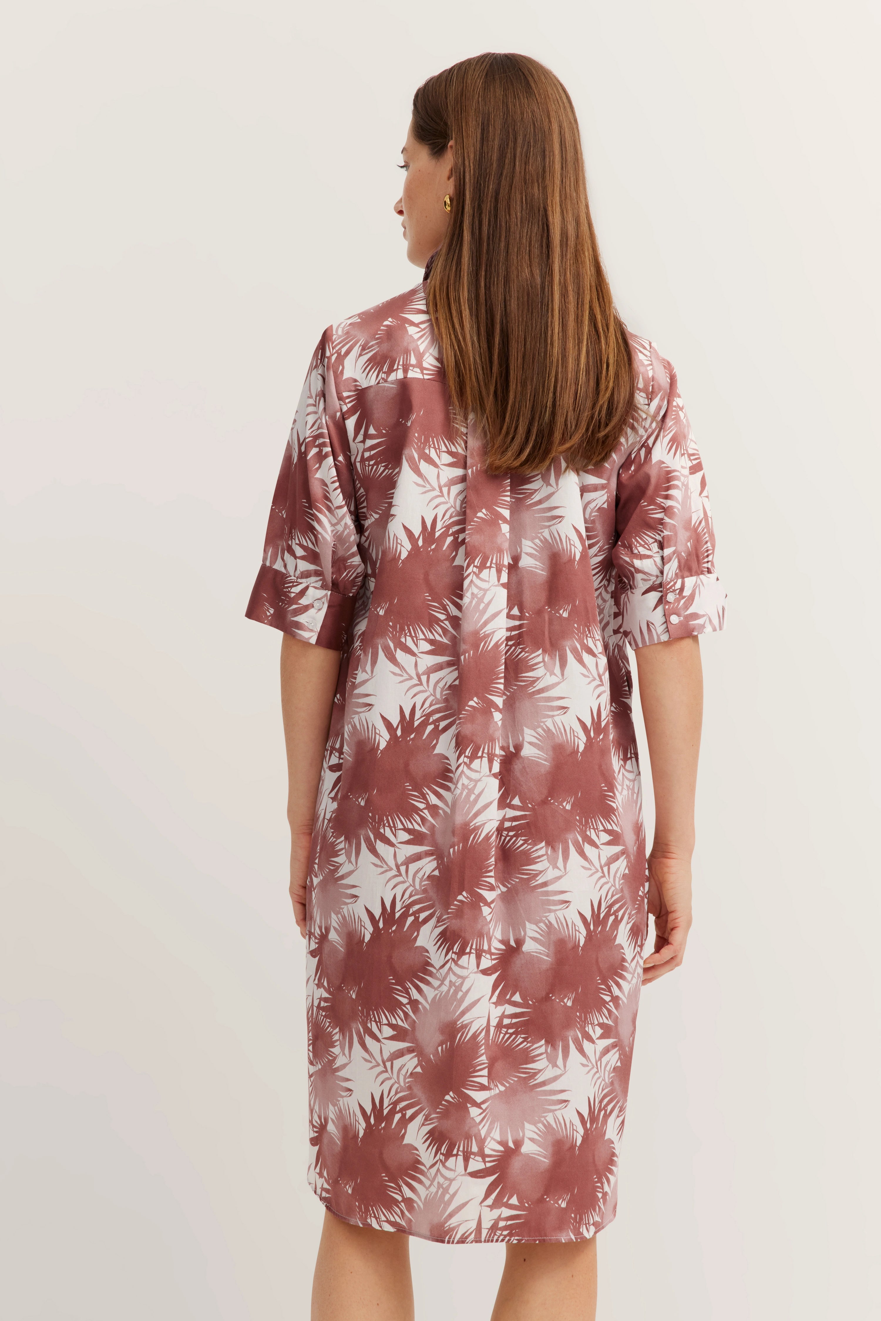 Model draagt rood-witte bloemenjurk. Achteraanzicht. Casual met halflange mouwen.