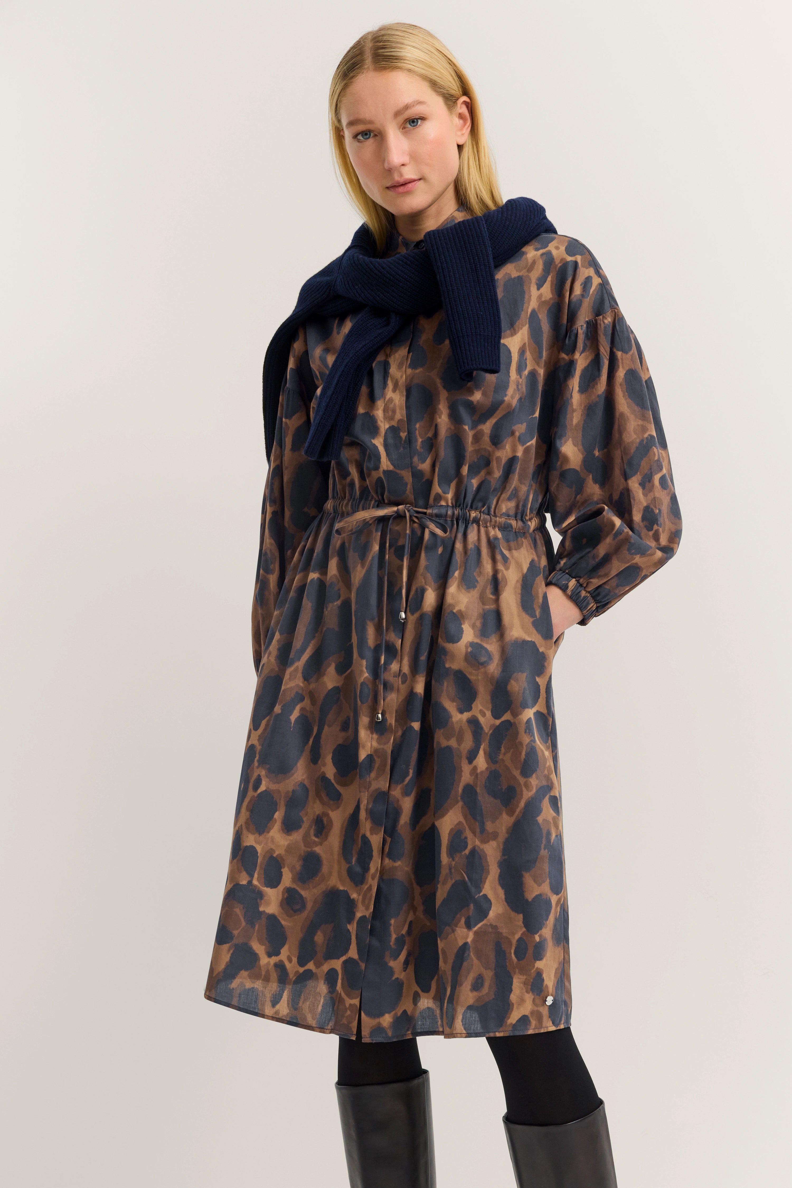 Model wears bugatti dress in brown and blue leopard print, with a blue jacket draped over shoulders.