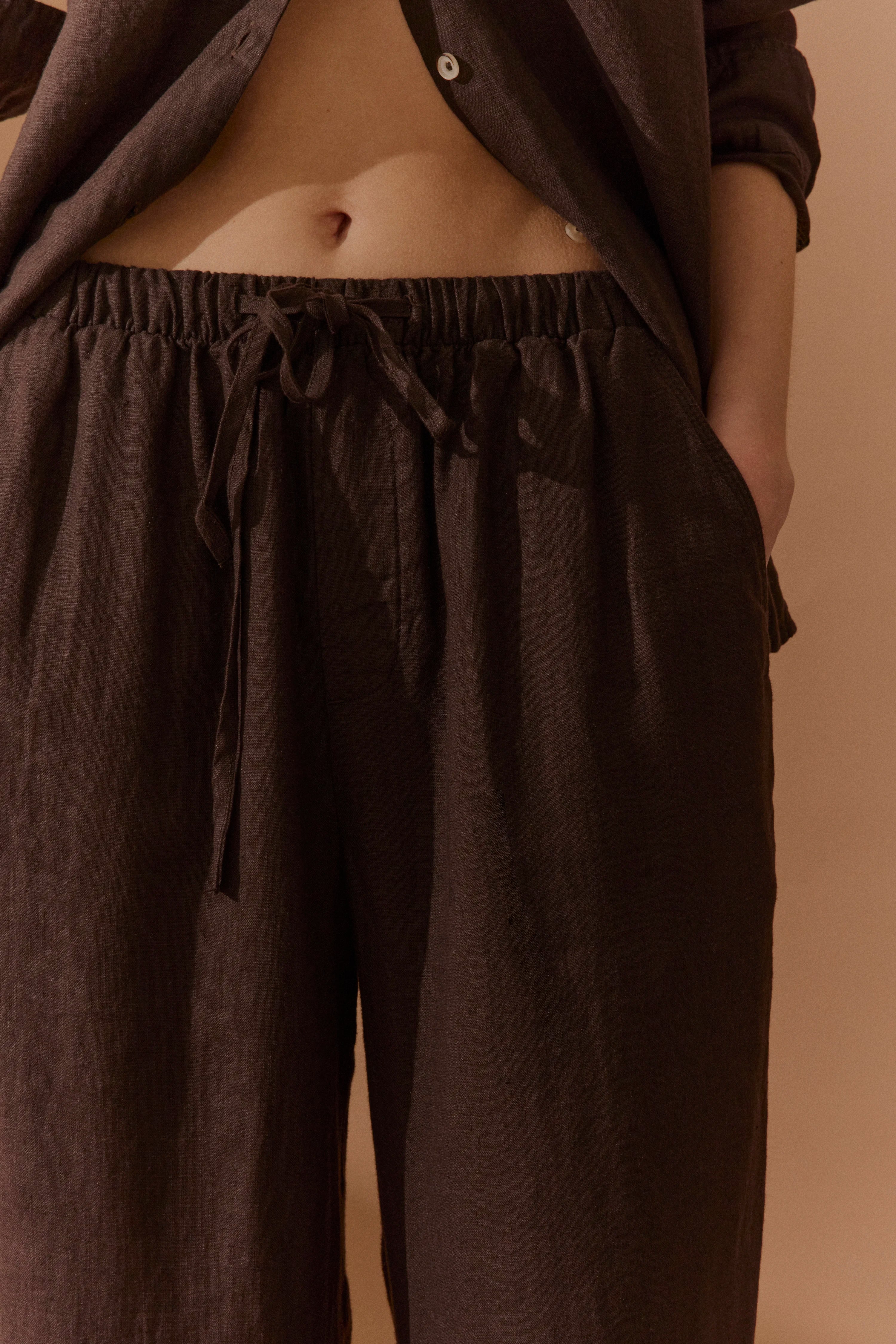 Braunes Leinenoutfit, bestehend aus offenem Hemd und Hose. Leger, Detailaufnahme.