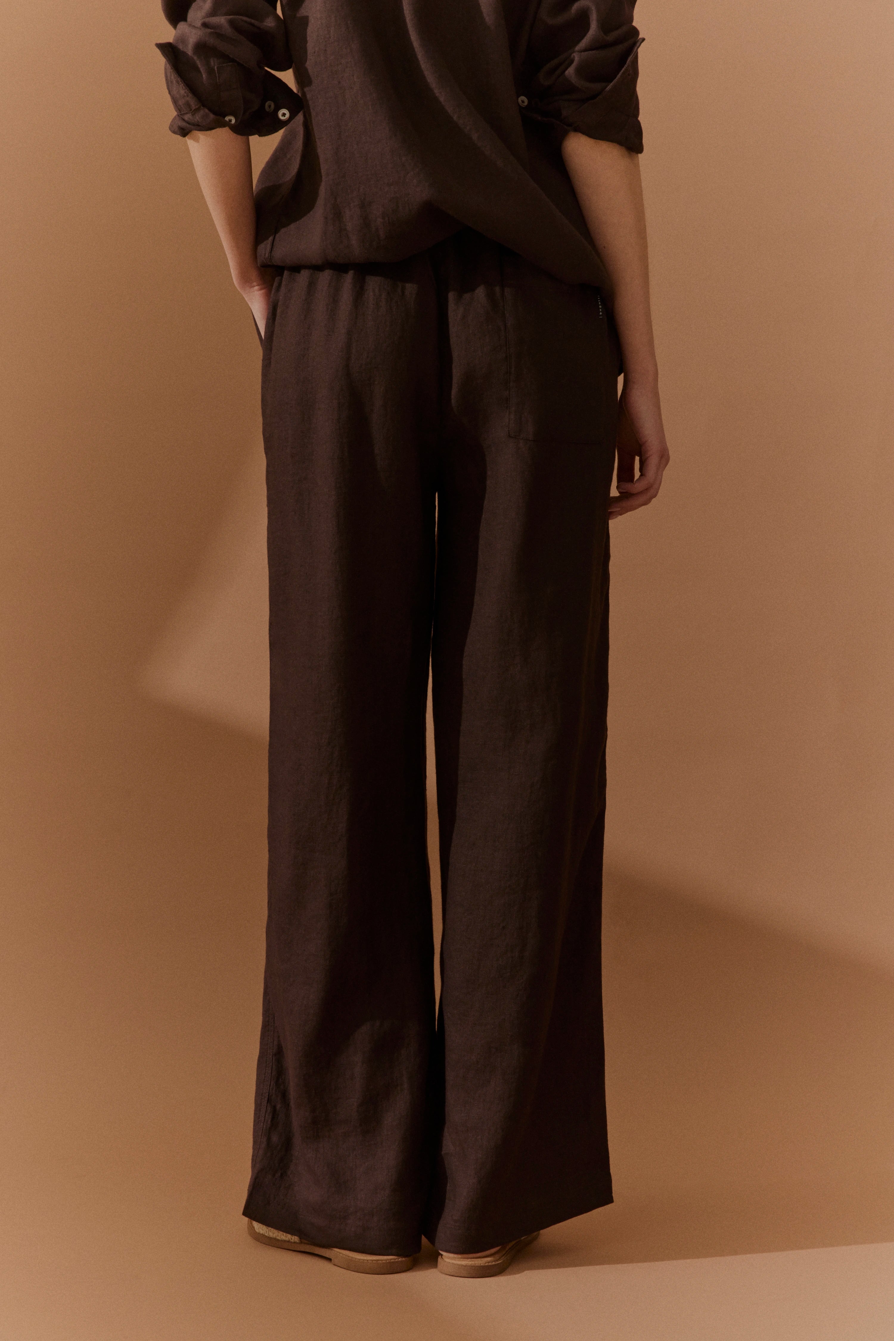 Braunes legeres Outfit von bugatti, bestehend aus lockerer Hose und Oberteil, Model steht locker.