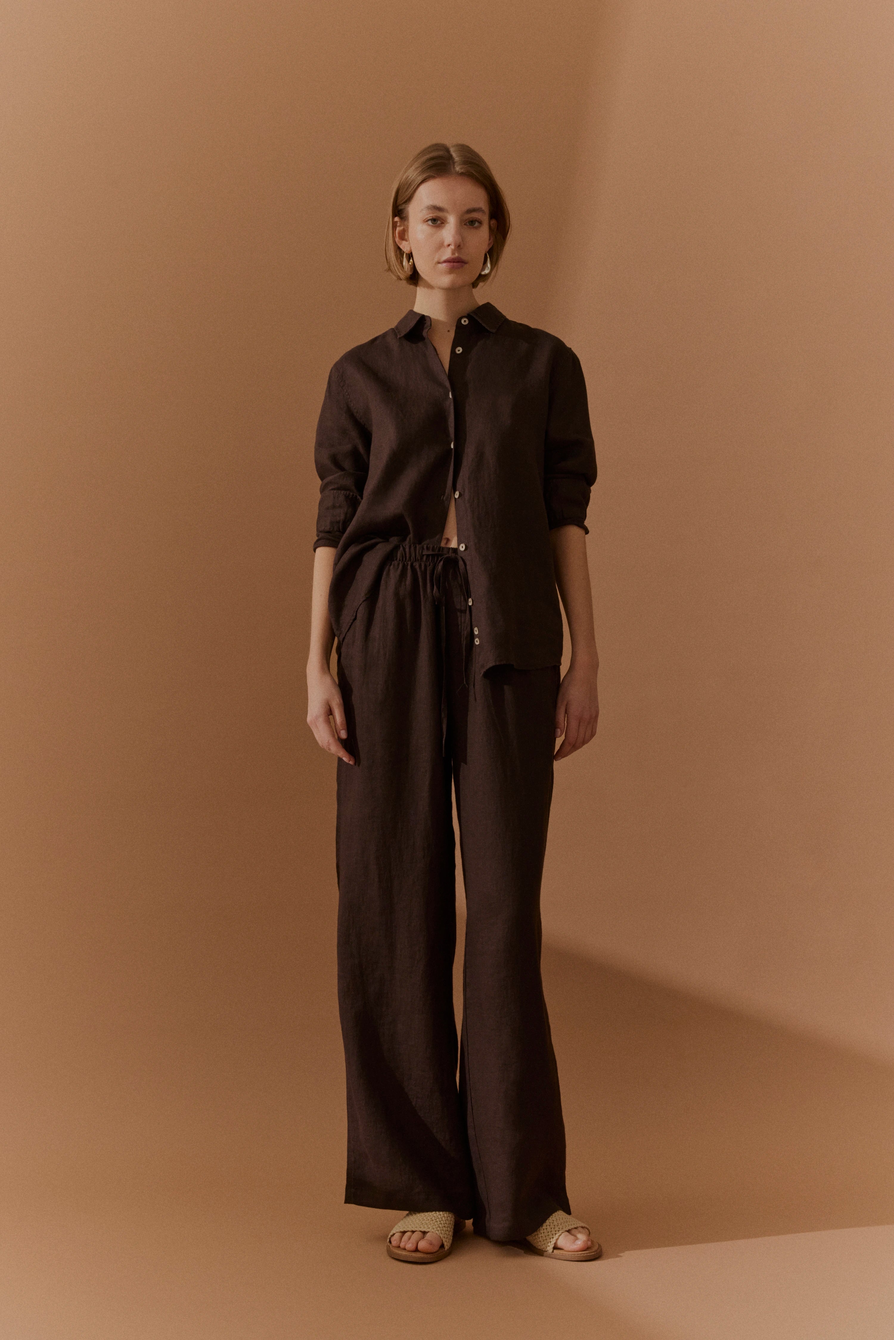 Model in brauner bugatti Leinenbluse und Hose, legeres Posing, natürliche Eleganz.