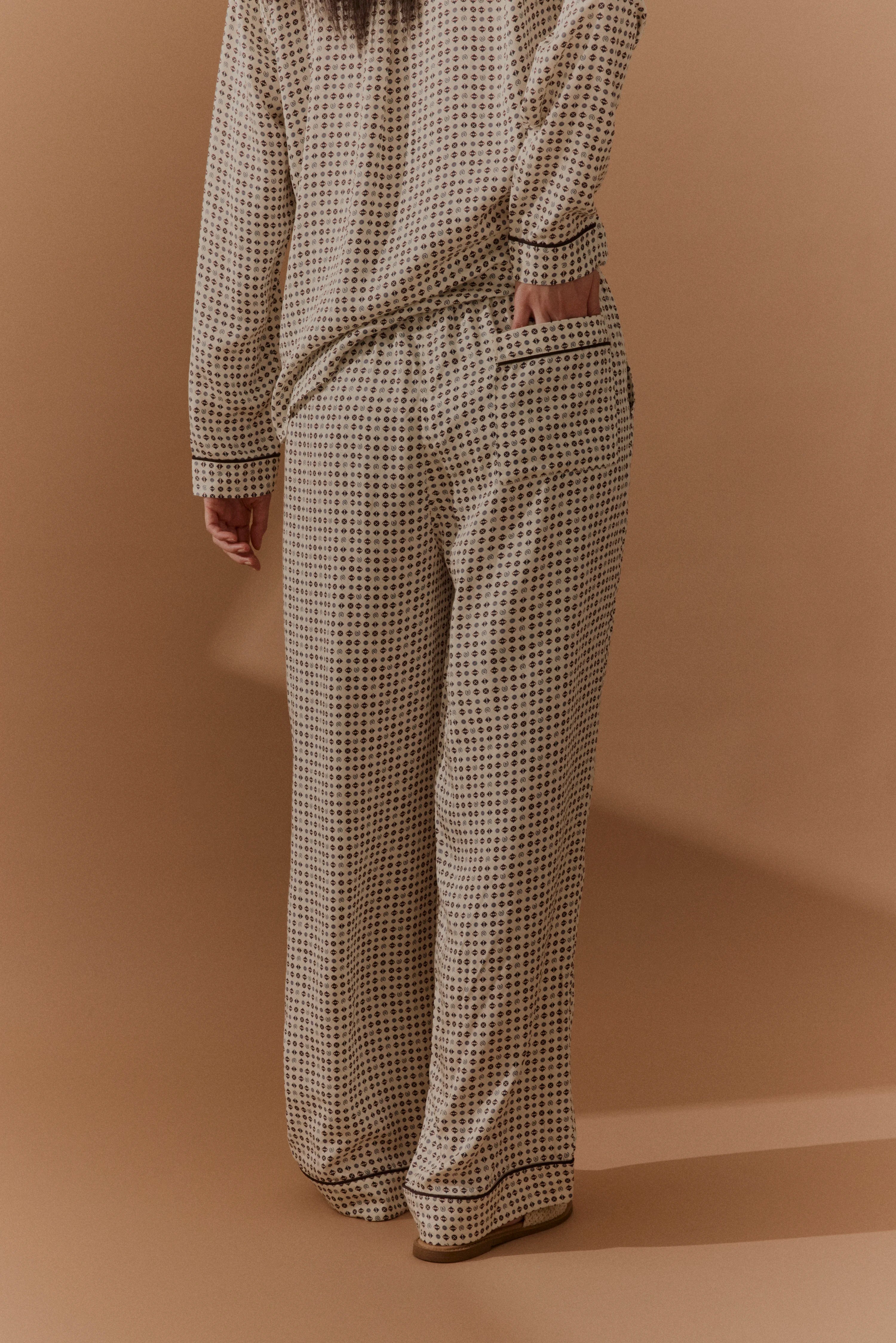 Beige gemustertes Outfit mit langer Hose und Shirt, Büstenbild von hinten, entspannter Stil.