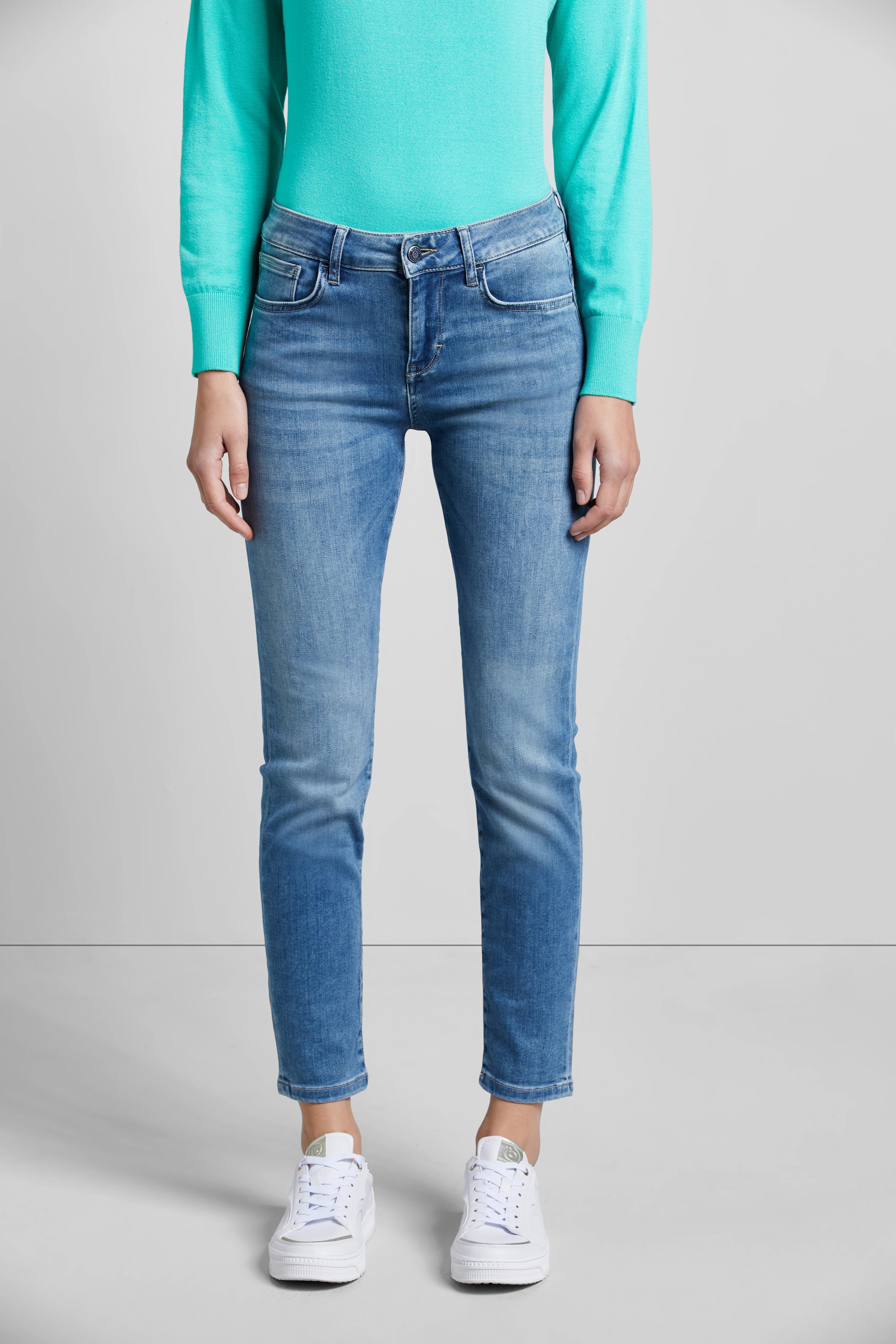 Türkiser Pullover, blaue Jeans, weiße Sneaker