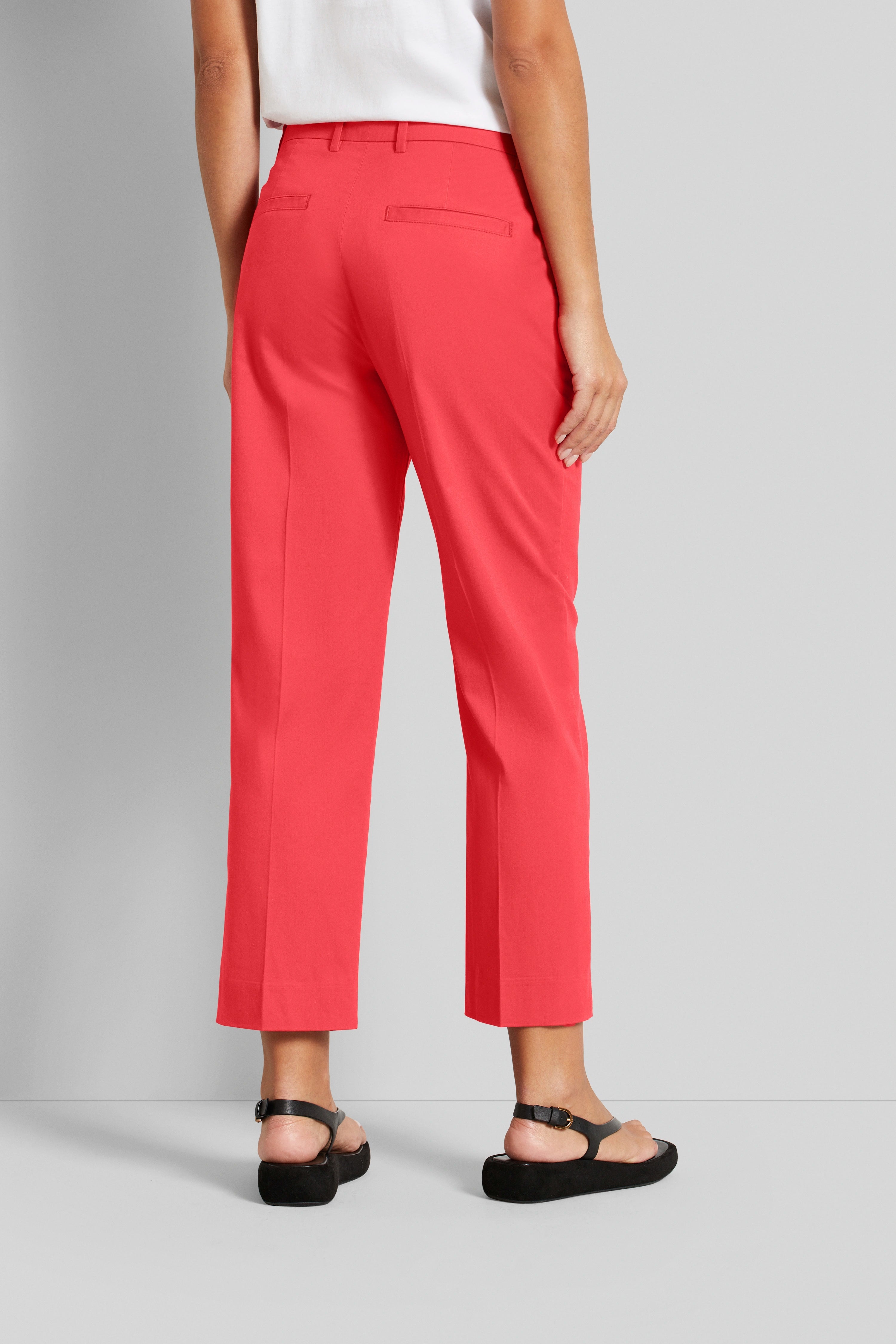 Achteraanzicht van rode bugatti broek, casual model, gecombineerd met zwarte sandalen.