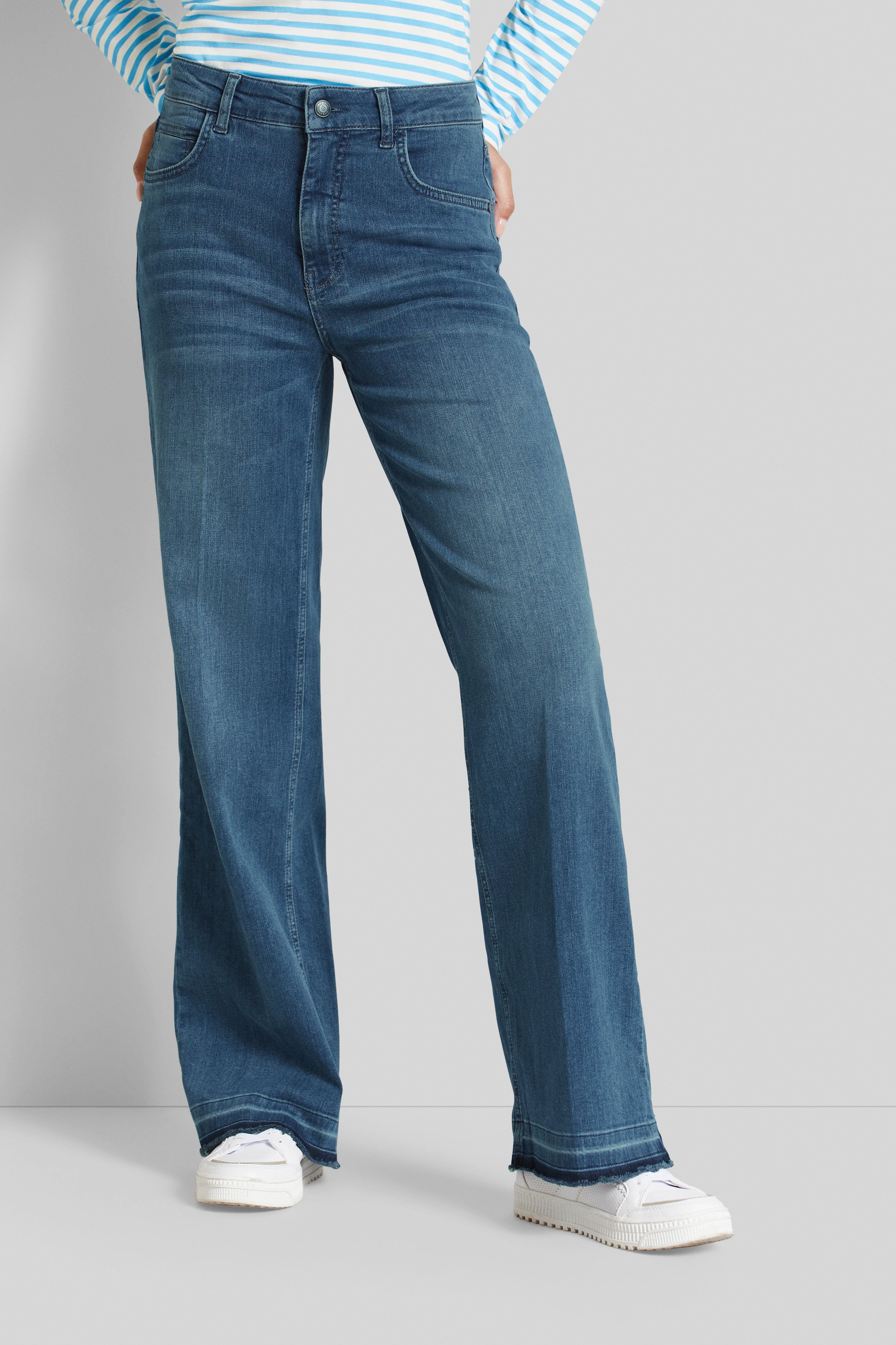 Blauwe wijde jeans met gestreept topje, ontspannen pose met handen in zakken. Elegantie en stijl door bugatti.