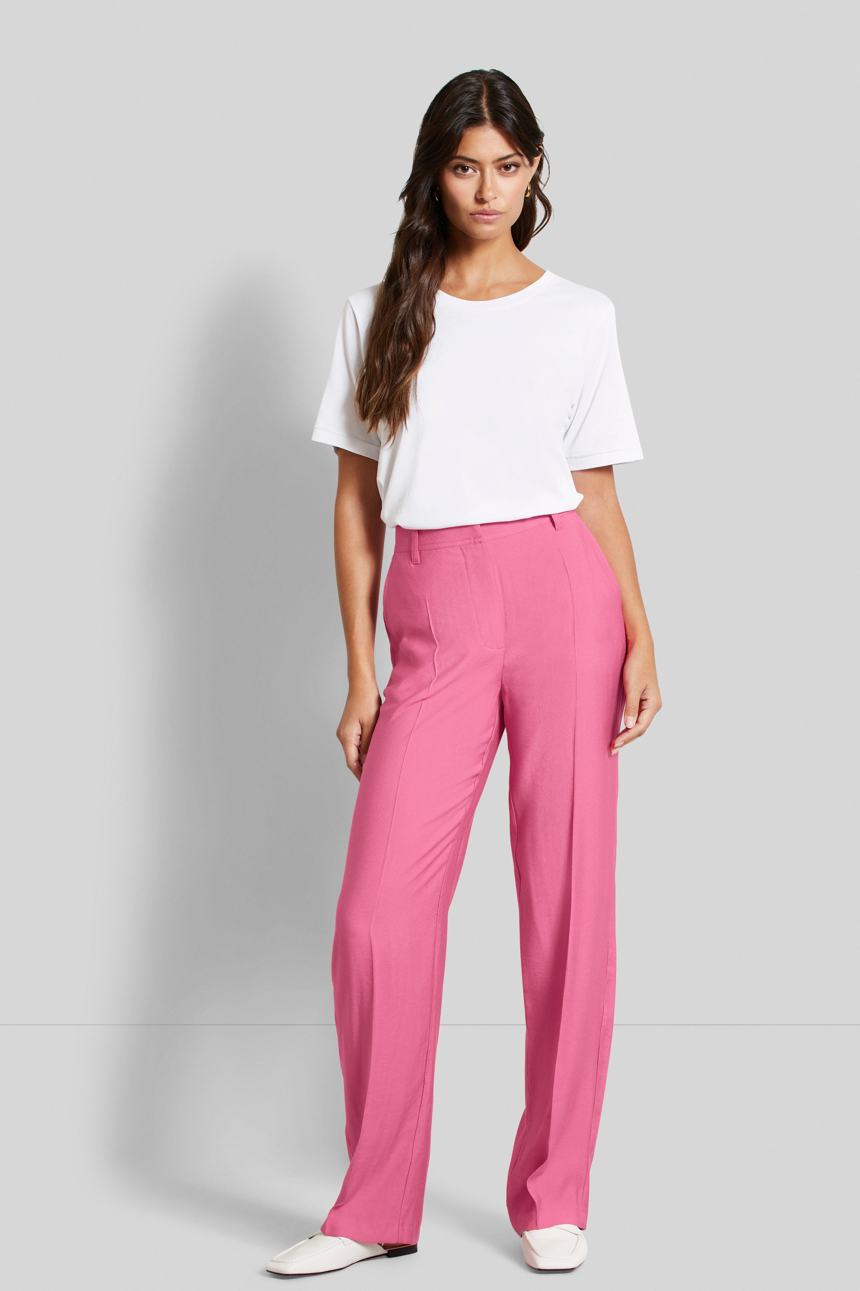 Wit T-shirt, roze broek, modelpose, ontspannen uitstraling.
